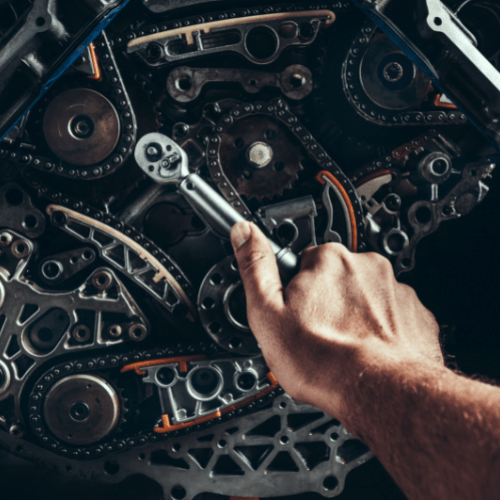 Hand using a wrench to adjust a complex metal machine mechanism with gears and chains