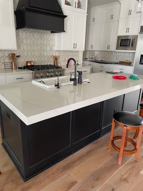 A kitchen with black cabinets and white counter tops