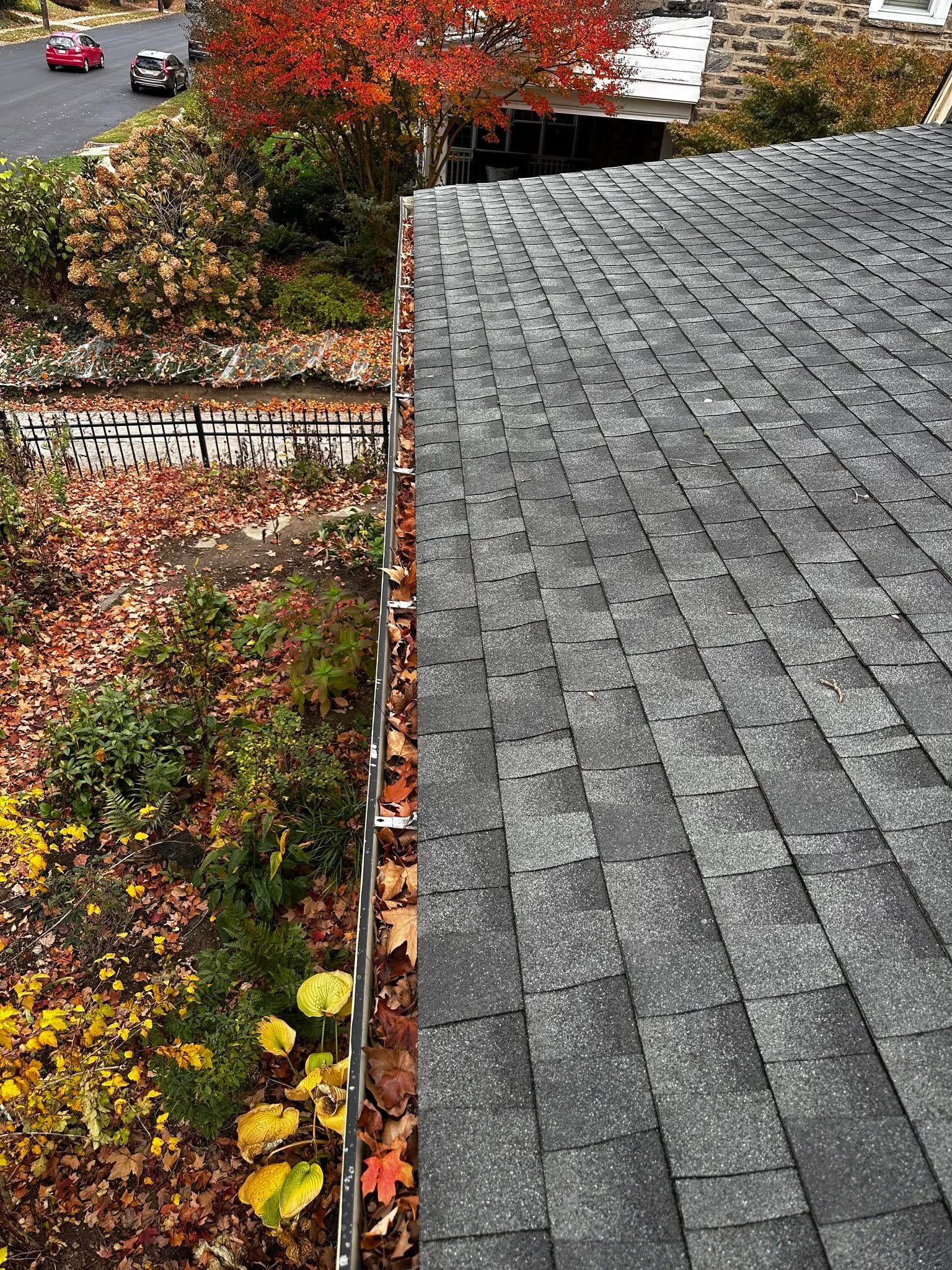 Gray shingled roof beside an autumn garden with red, yellow, and green foliage