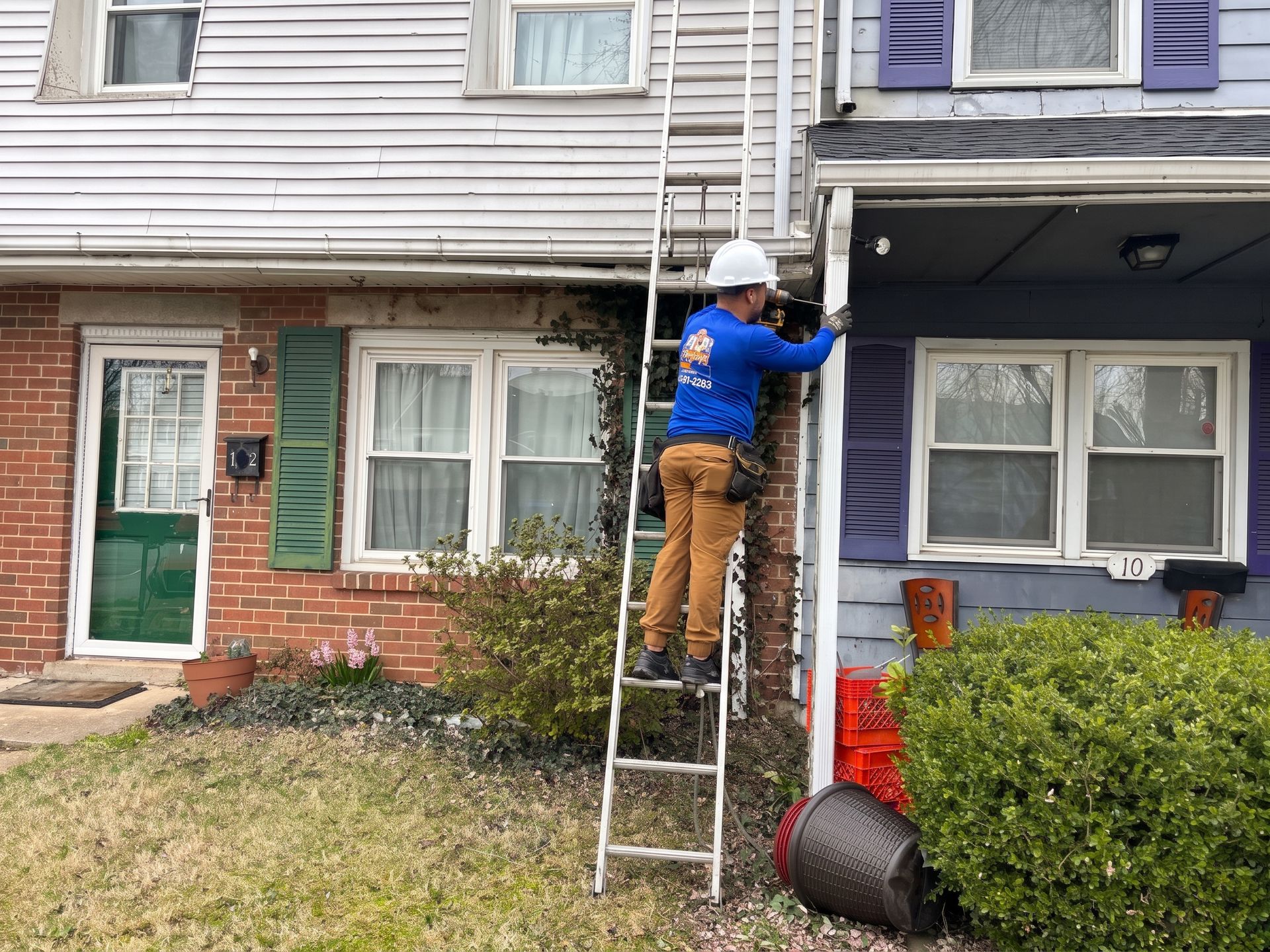 Person on ladder painting the trim of a townhouse exterior