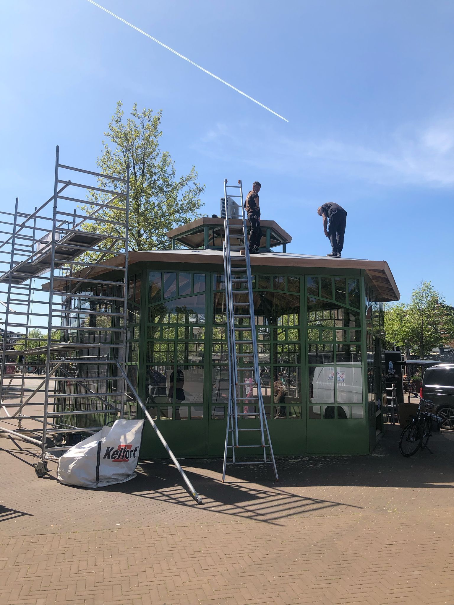 Een man op een ladder werkt op het dak van een gebouw.