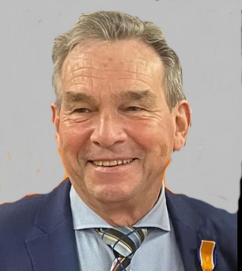 Een man in pak en stropdas lacht naar de camera.