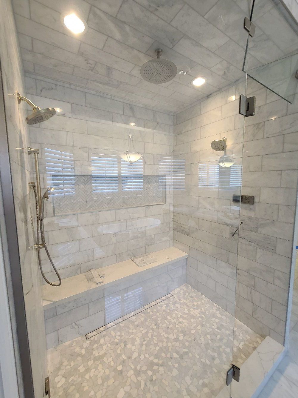 A bathroom with a walk in shower with a glass door.