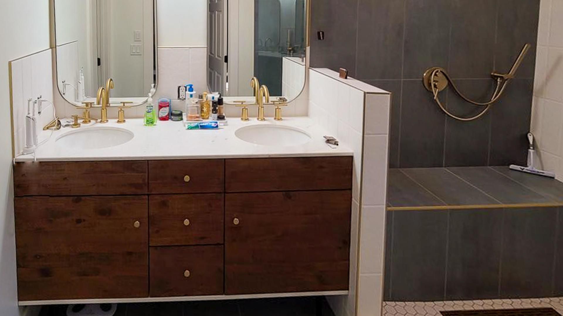 A bathroom with two sinks and a walk in shower.