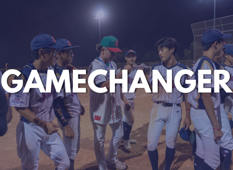 Youth baseball players huddle on a lit dirt field at night, with “GAMECHANGER” overlaid across the image.