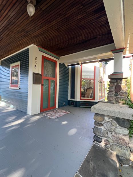 A blue and white house with a red door and a porch