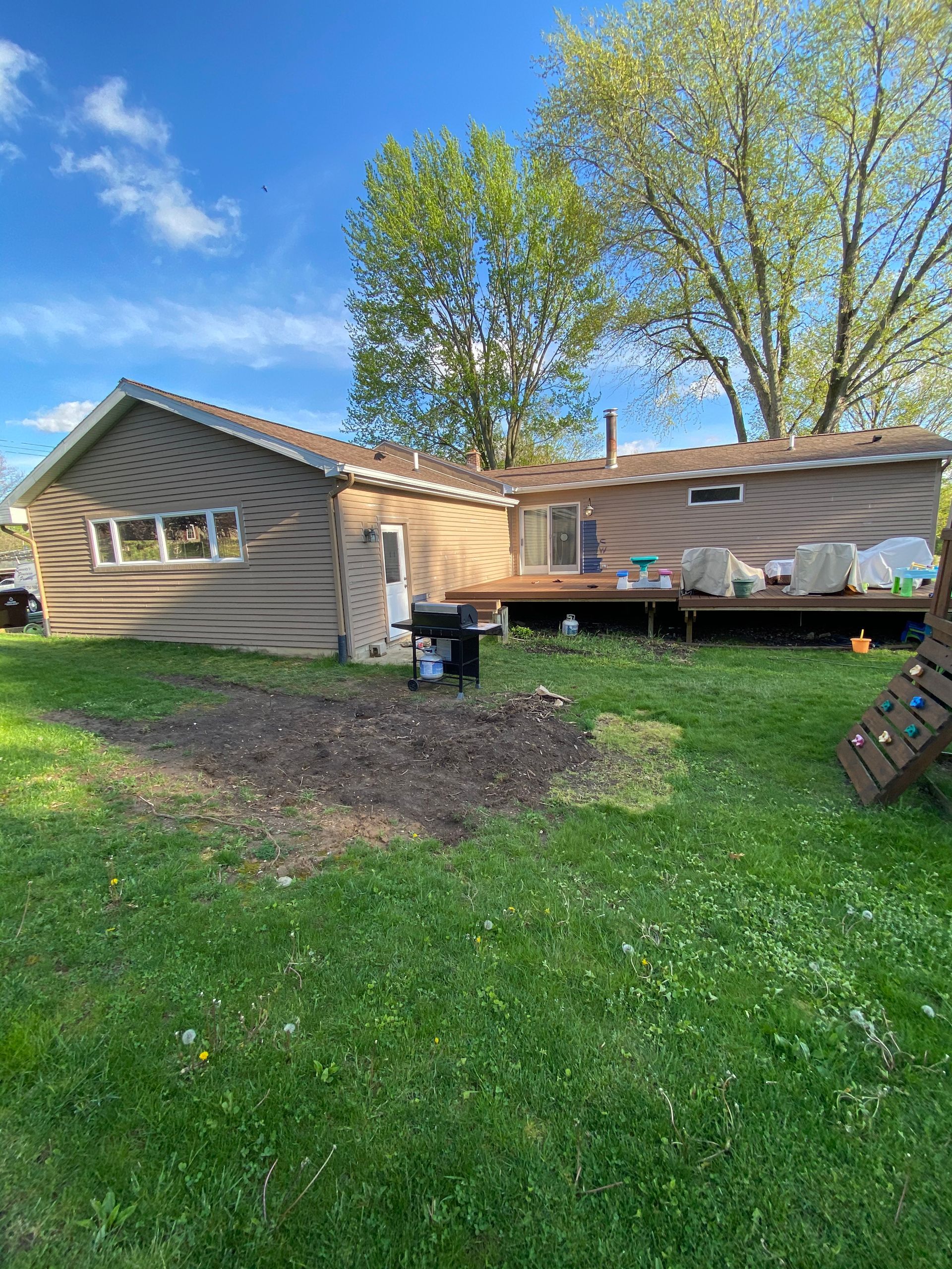 The backyard of a house with a large lawn and a deck.