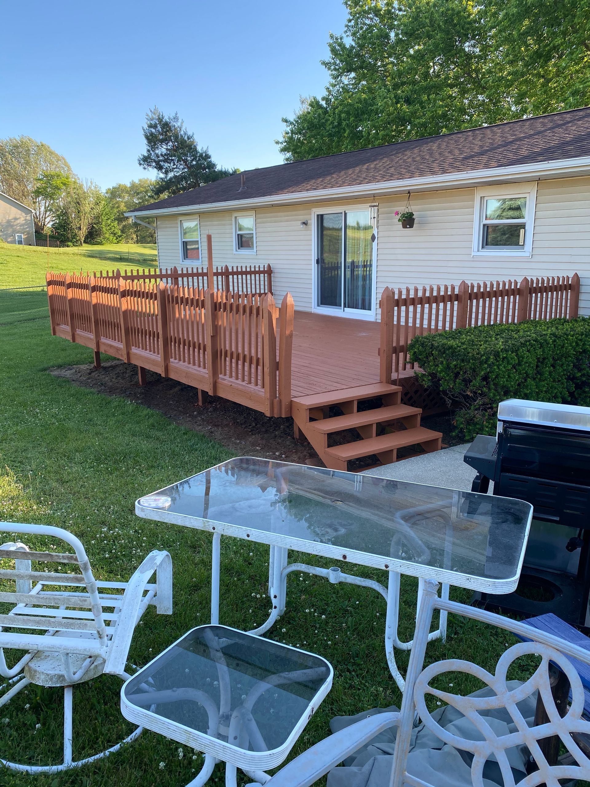A house with a large deck and a table and chairs in front of it.