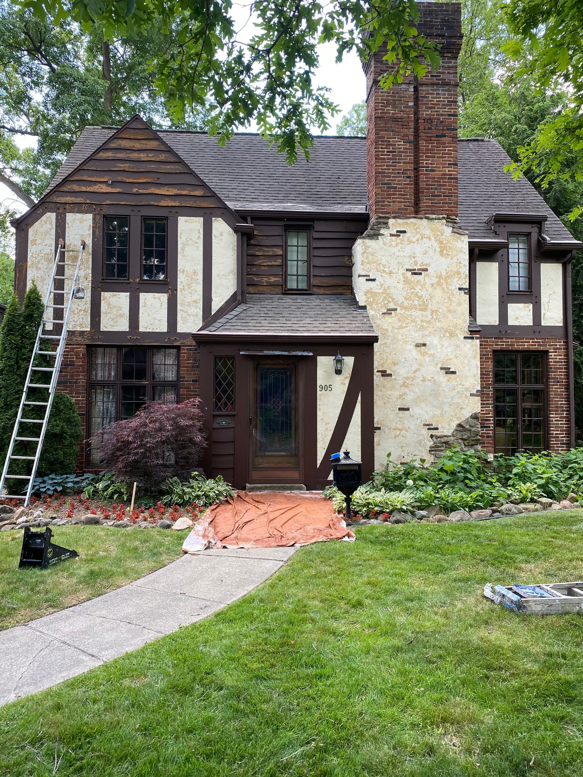 A house with a ladder on the side of it is being painted.