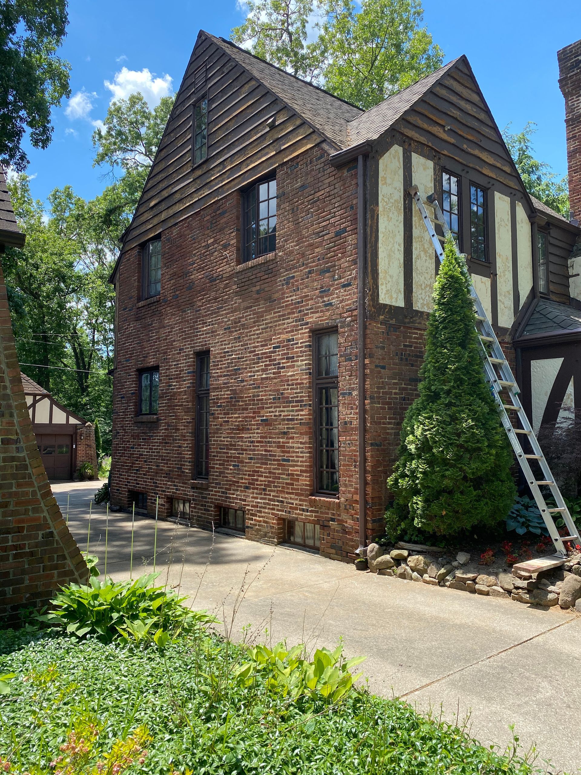 A large brick house with a ladder in front of it.