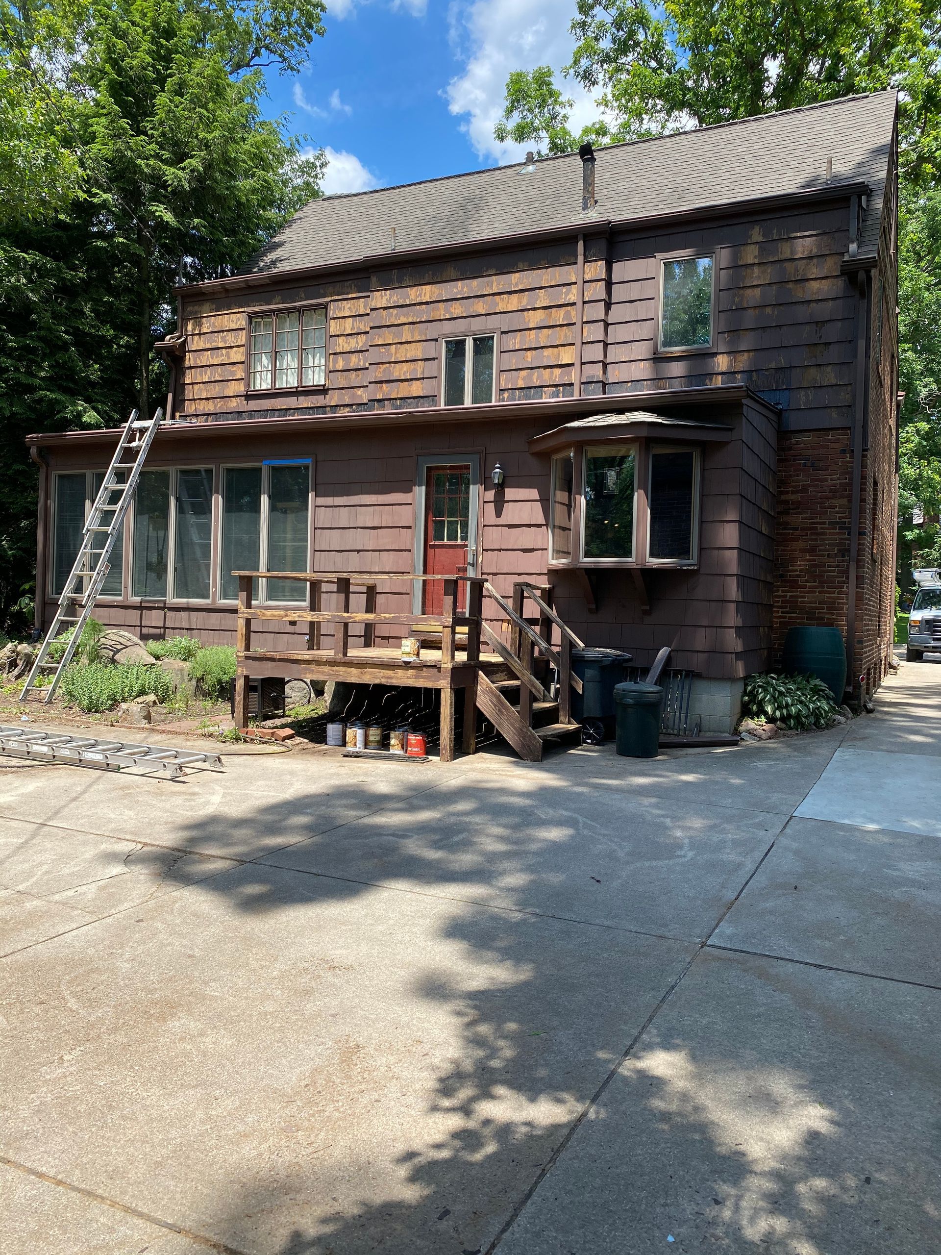 A house with a ladder on the side of it and a driveway in front of it.