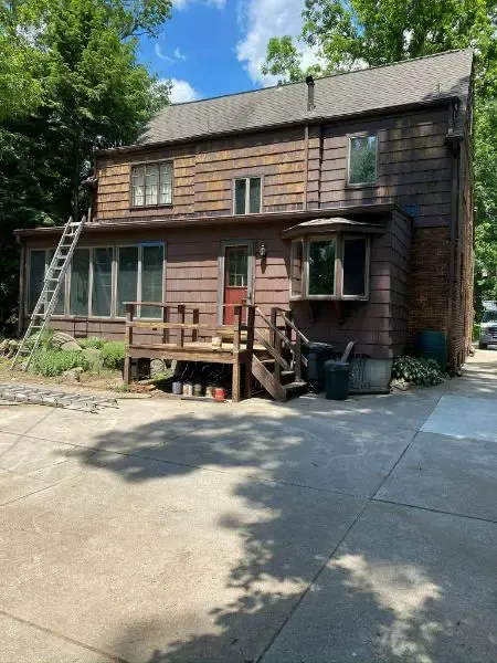 A large brown house with a ladder in front of it