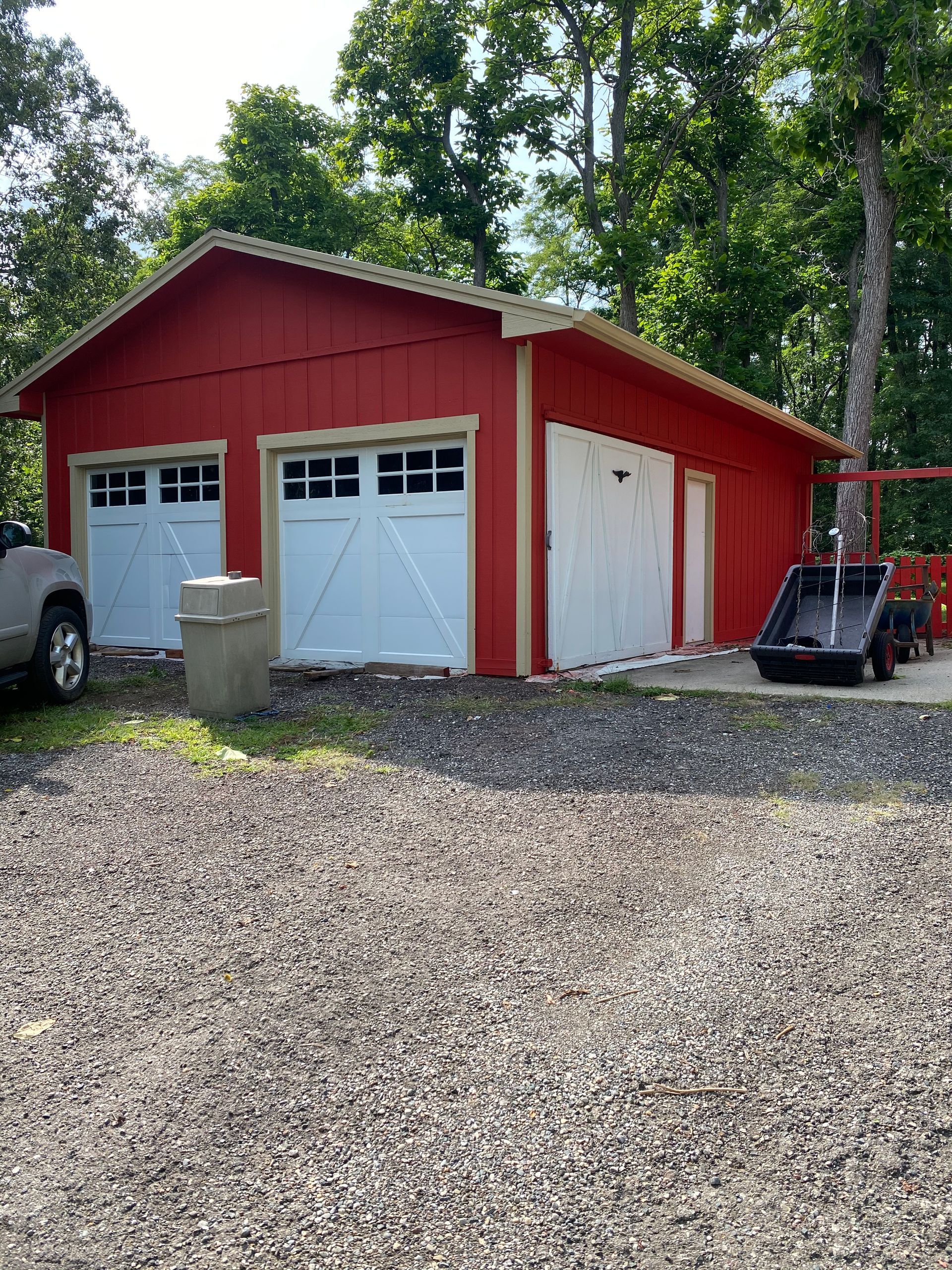 A red garage with white doors and a truck parked in front of it.