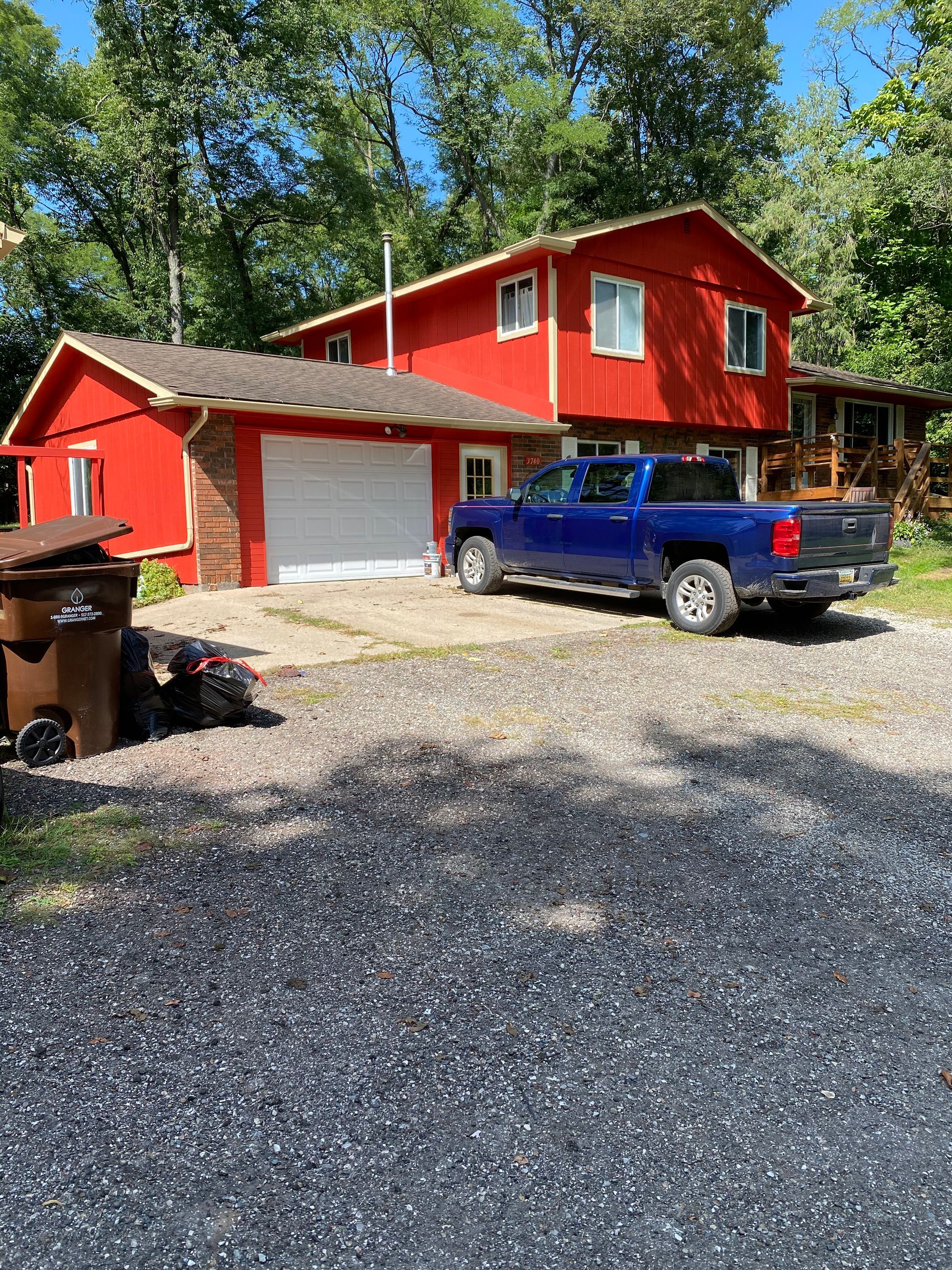 A blue truck is parked in front of a red house.