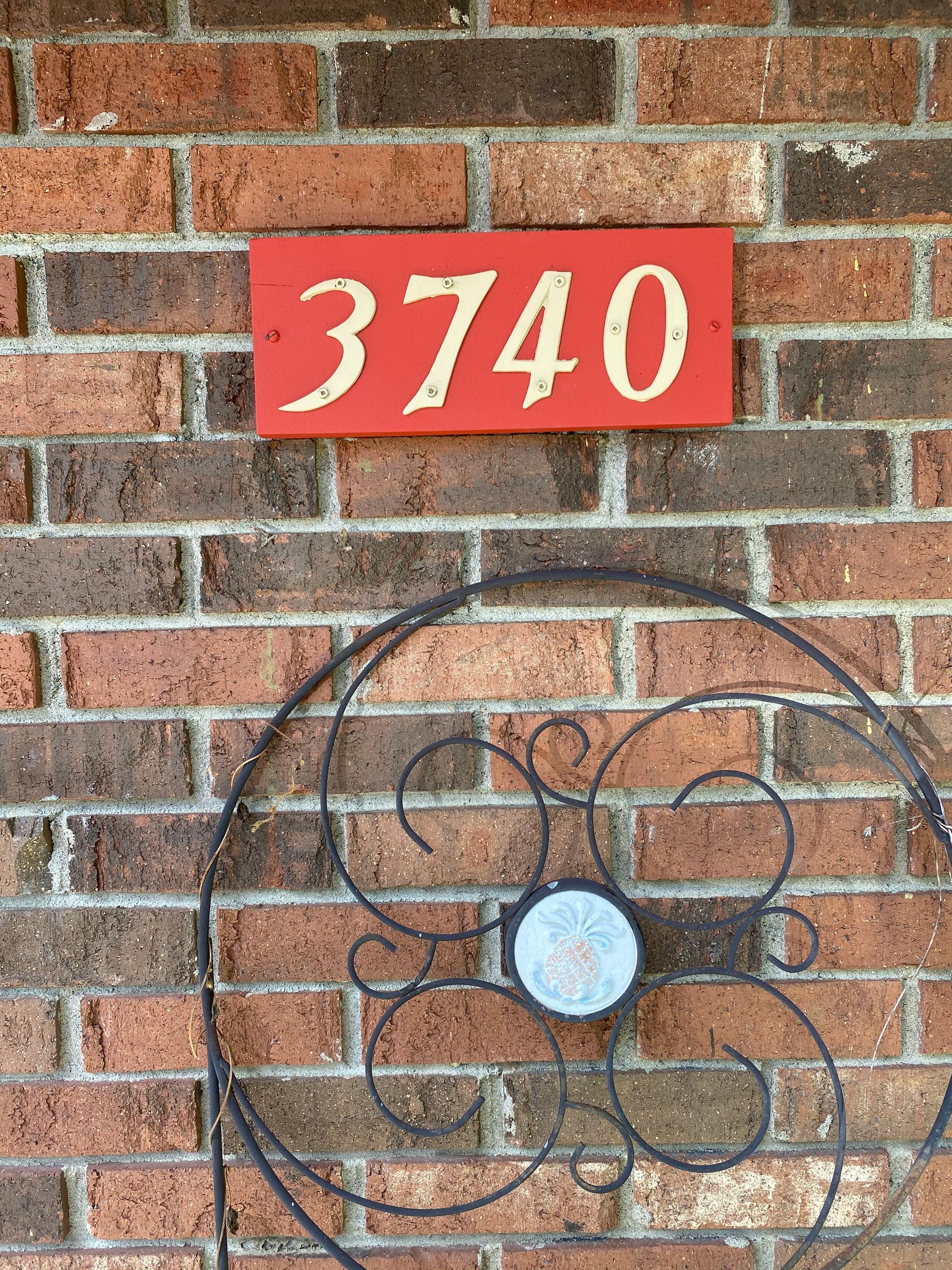 A red sign on a brick wall says 3740