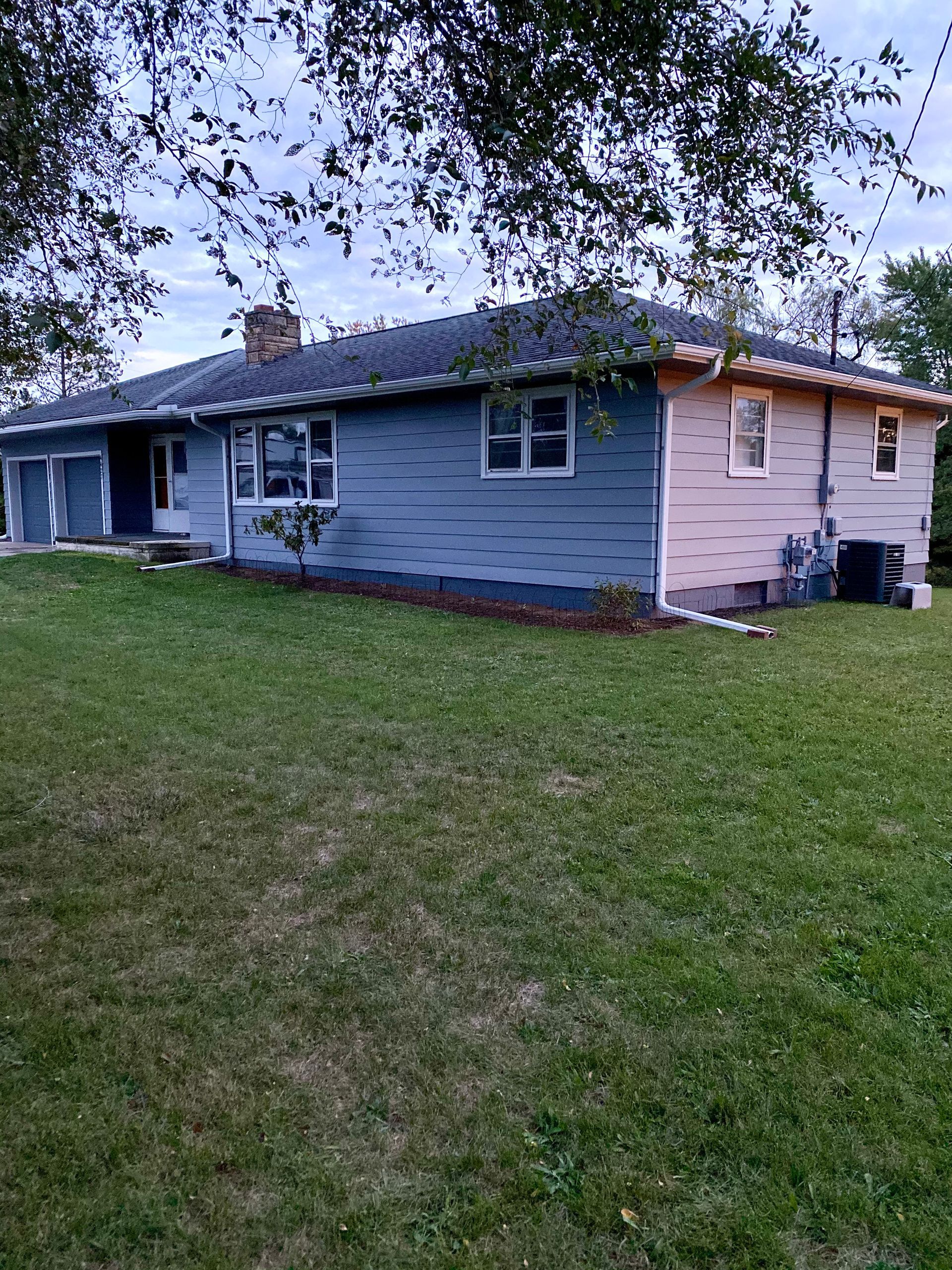 A blue and pink house is sitting on top of a lush green lawn.