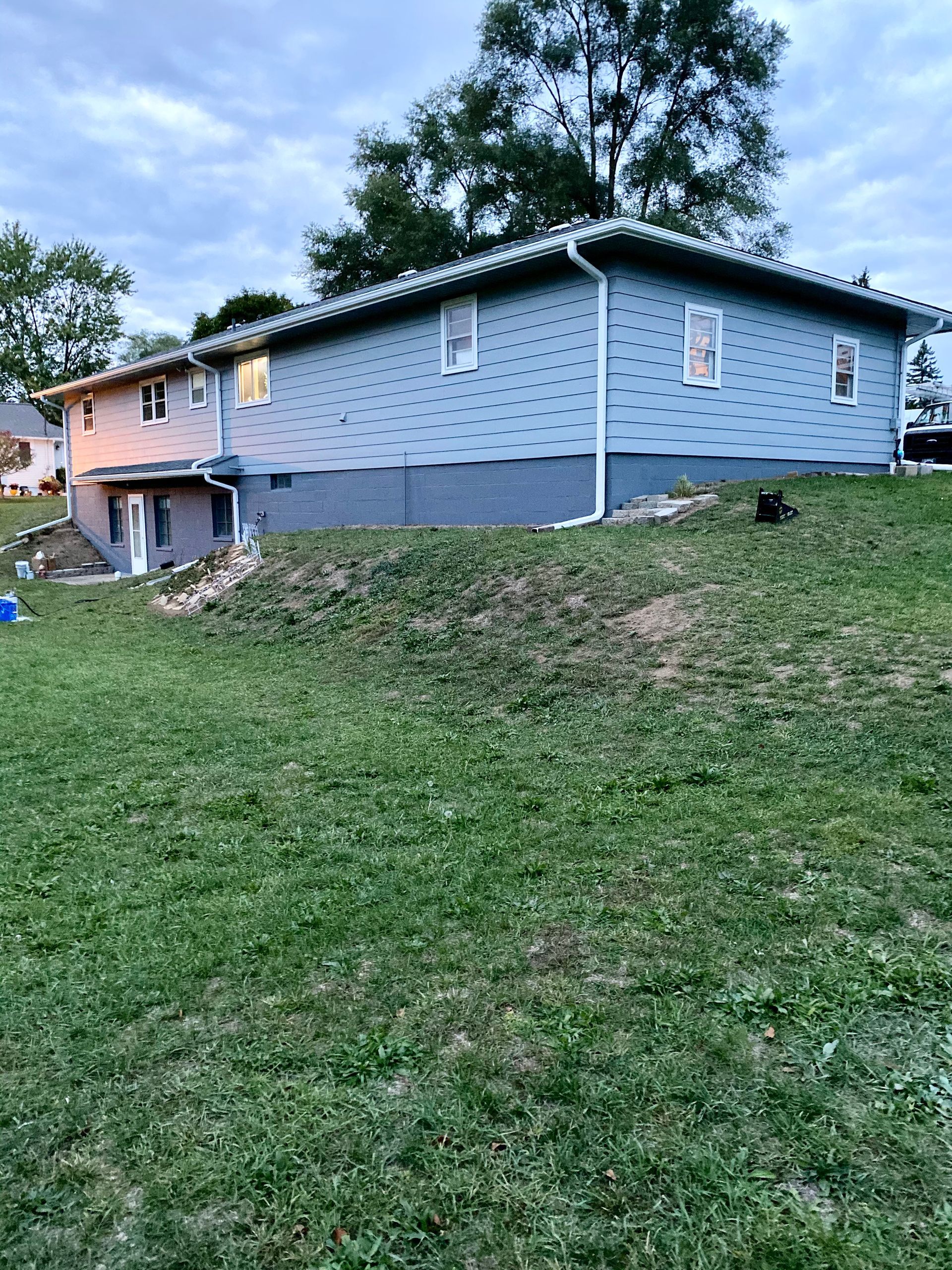 A house is sitting on top of a grassy hill.
