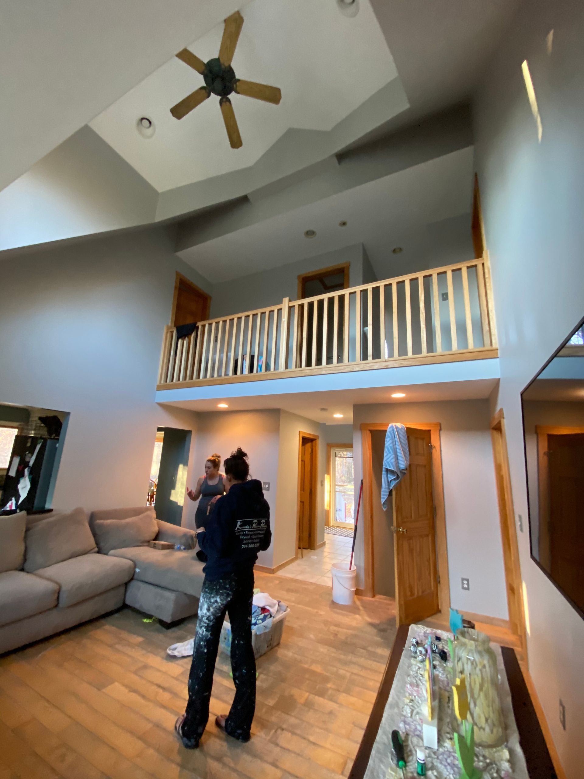 A man is standing in a living room with a ceiling fan.