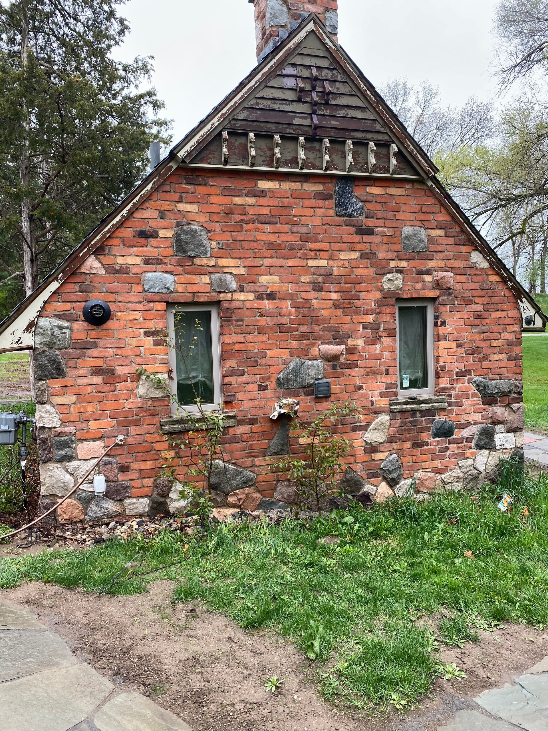A small brick house with a stone roof and a chimney.