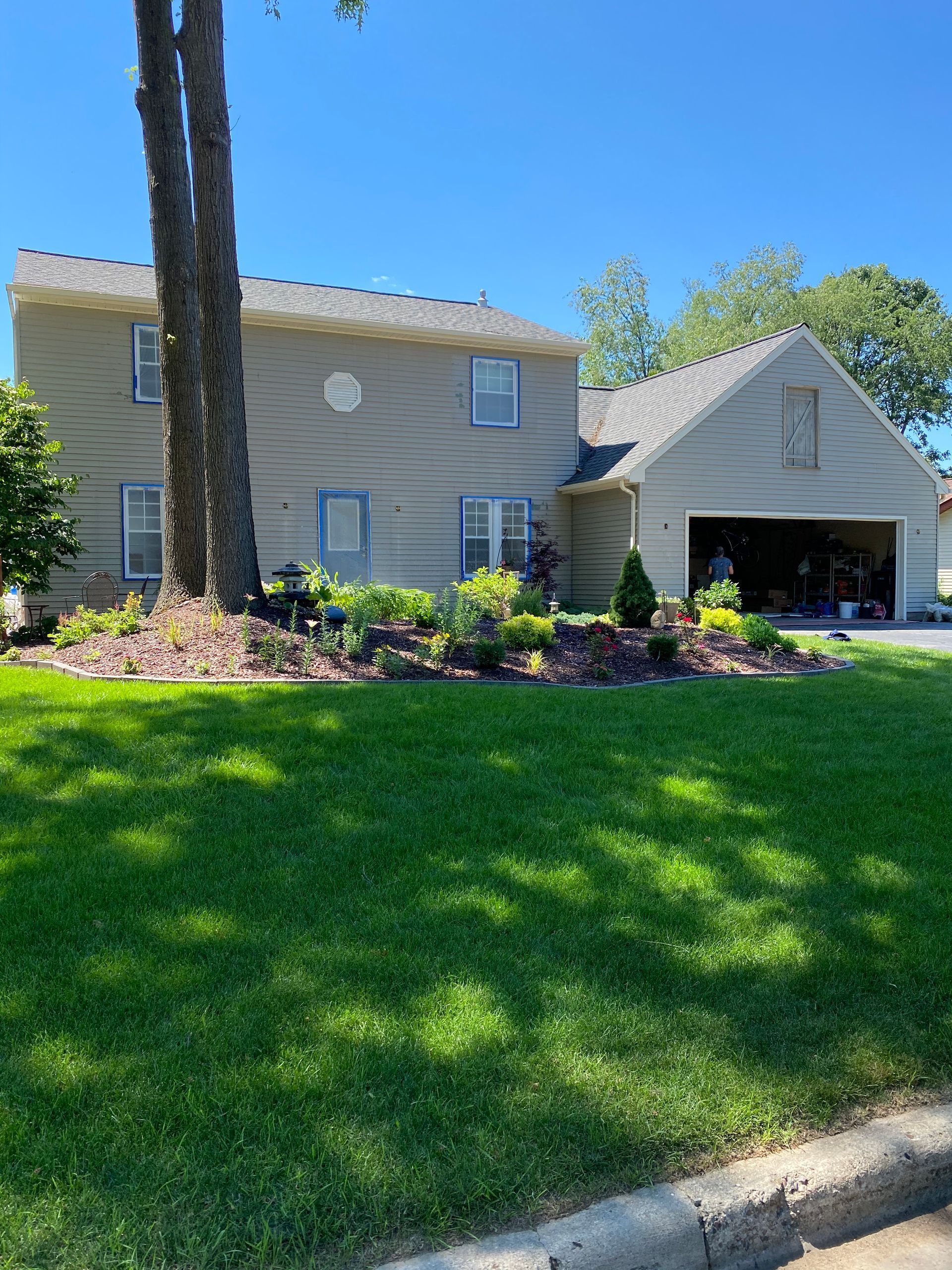 A large house with a garage and a large lawn in front of it.