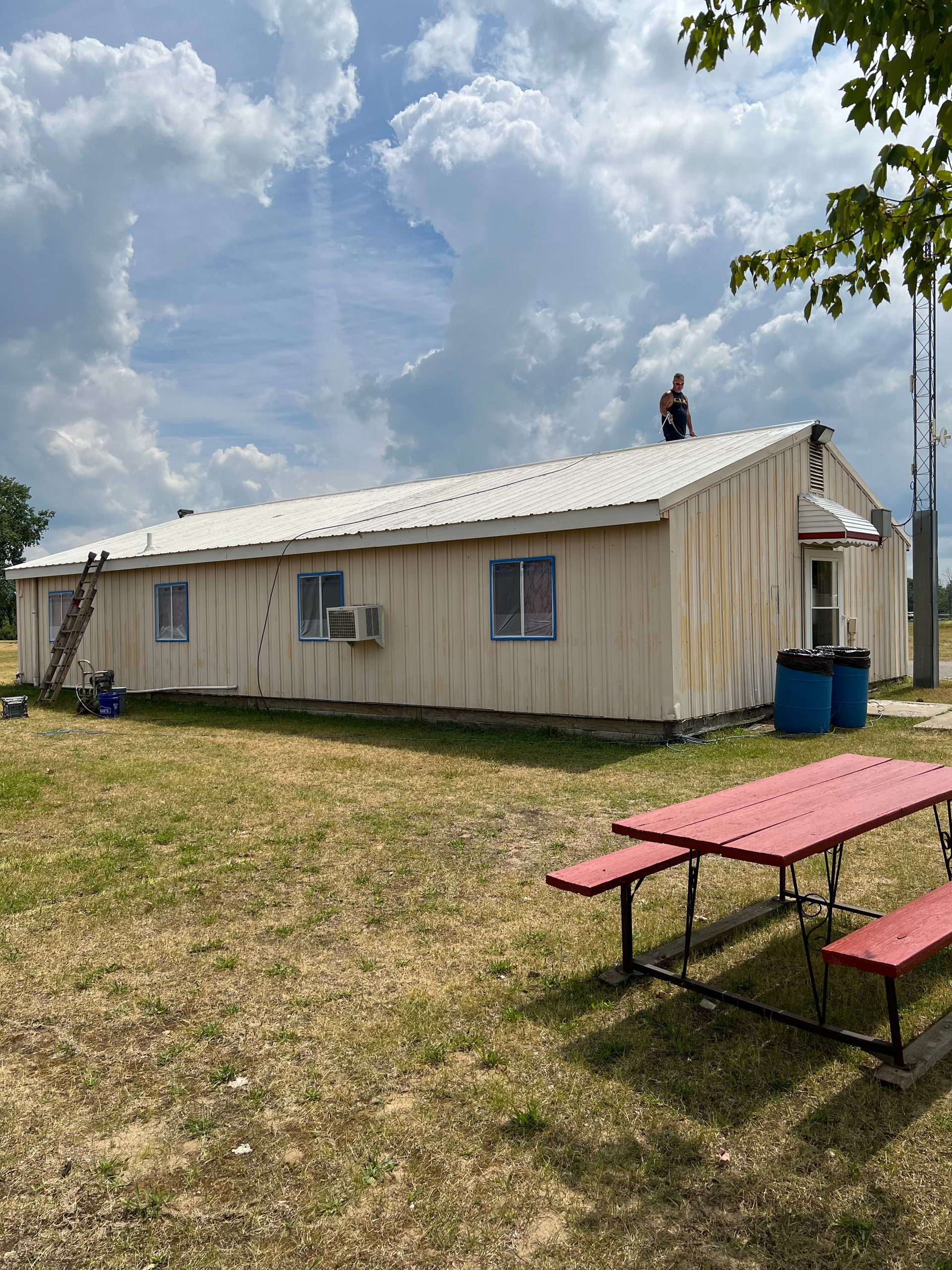 A man is standing on the roof of a building next to a picnic table.