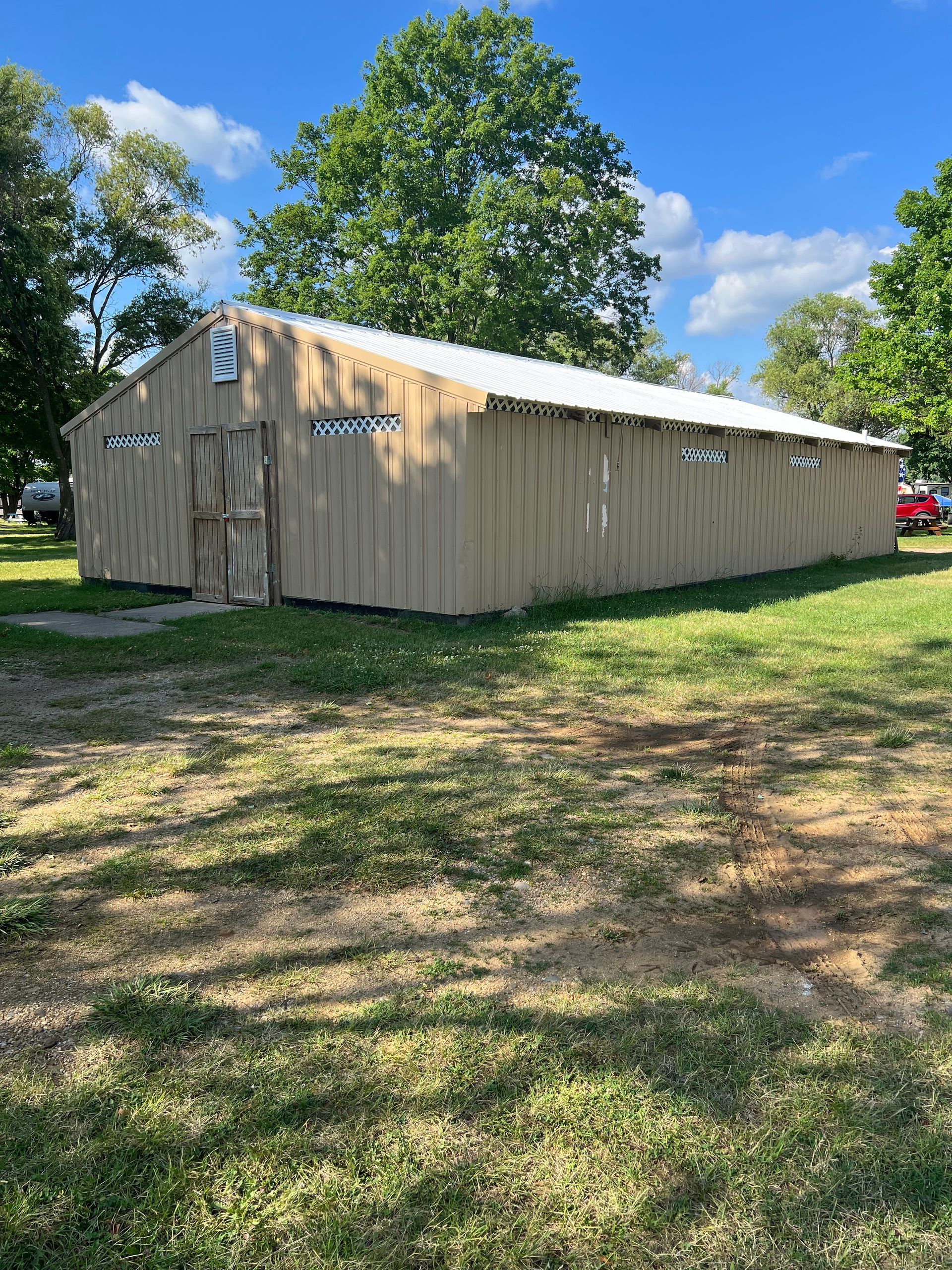 A large wooden building is sitting in the middle of a grassy field.