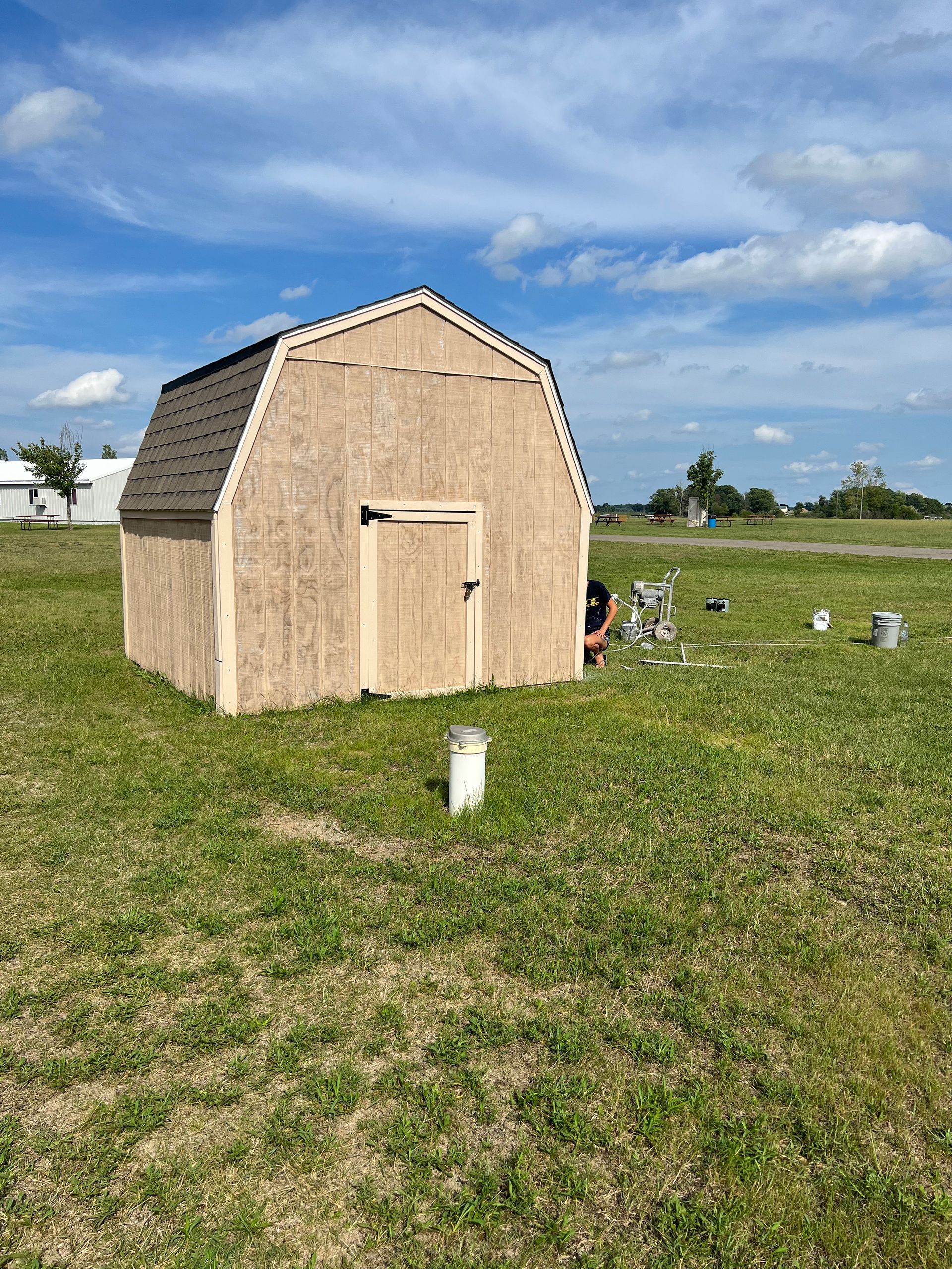 A small barn is sitting in the middle of a grassy field.