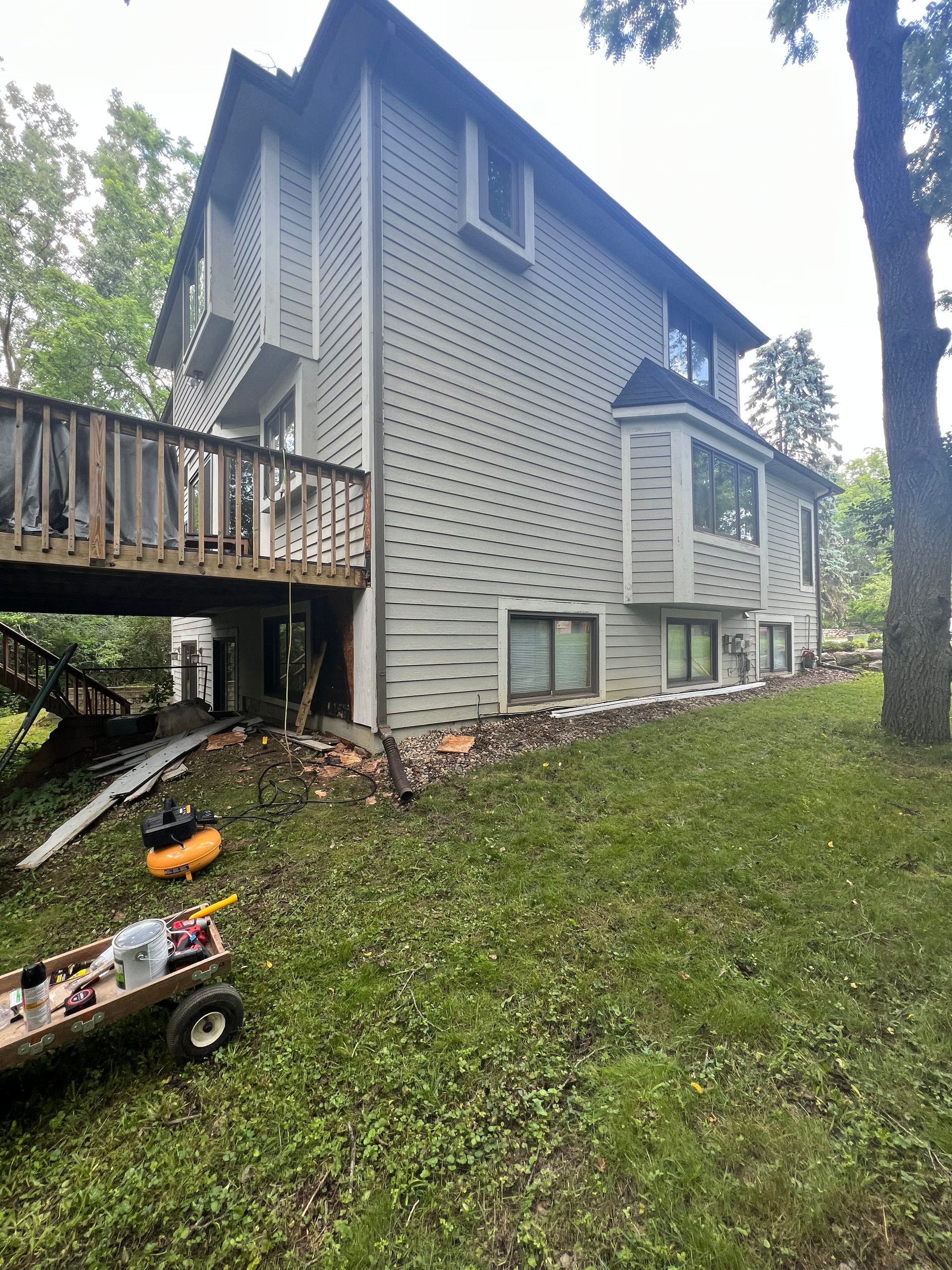 A large house with a deck and a wheelbarrow in front of it.