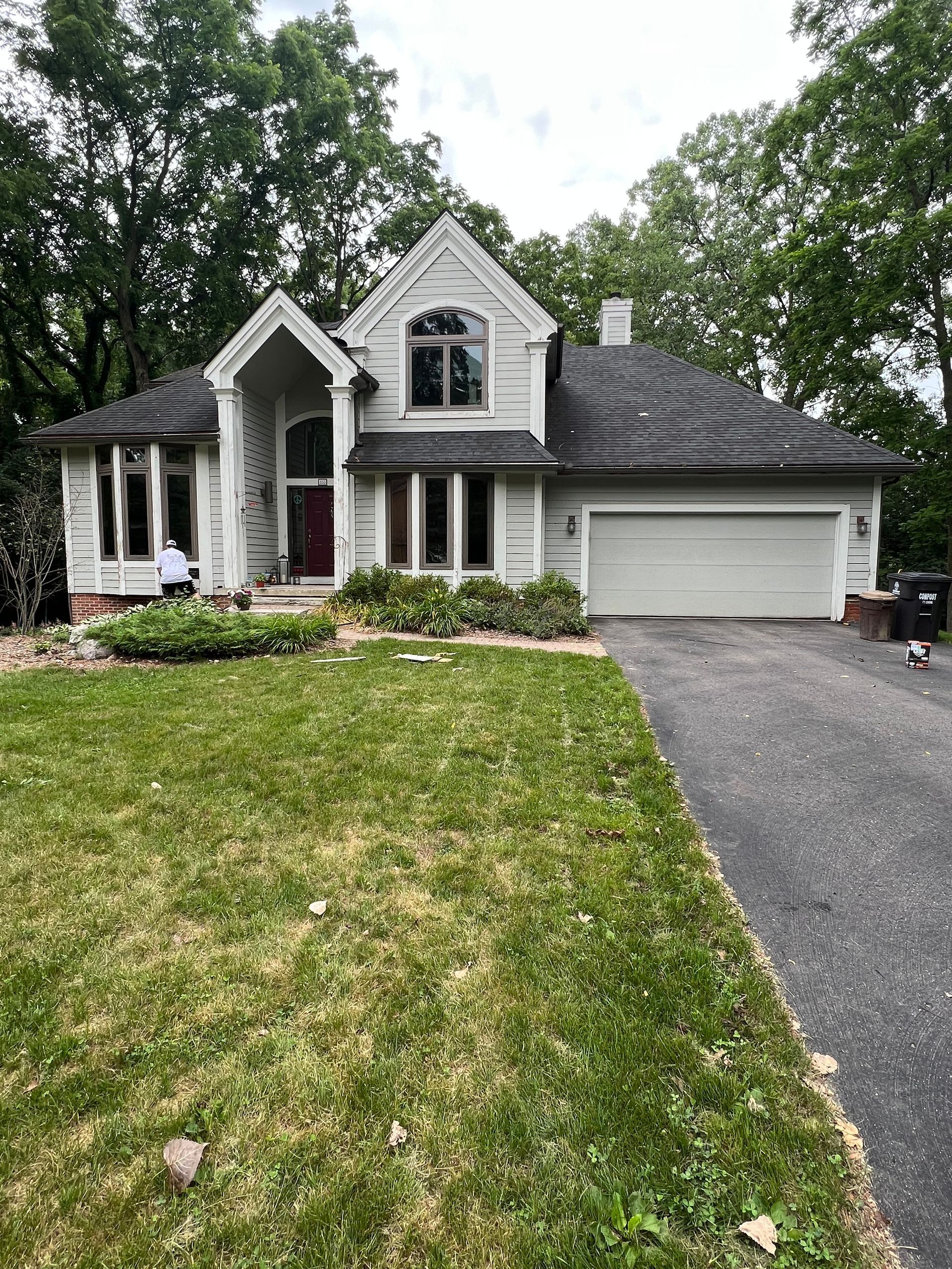 A large white house with a gray roof and a driveway.