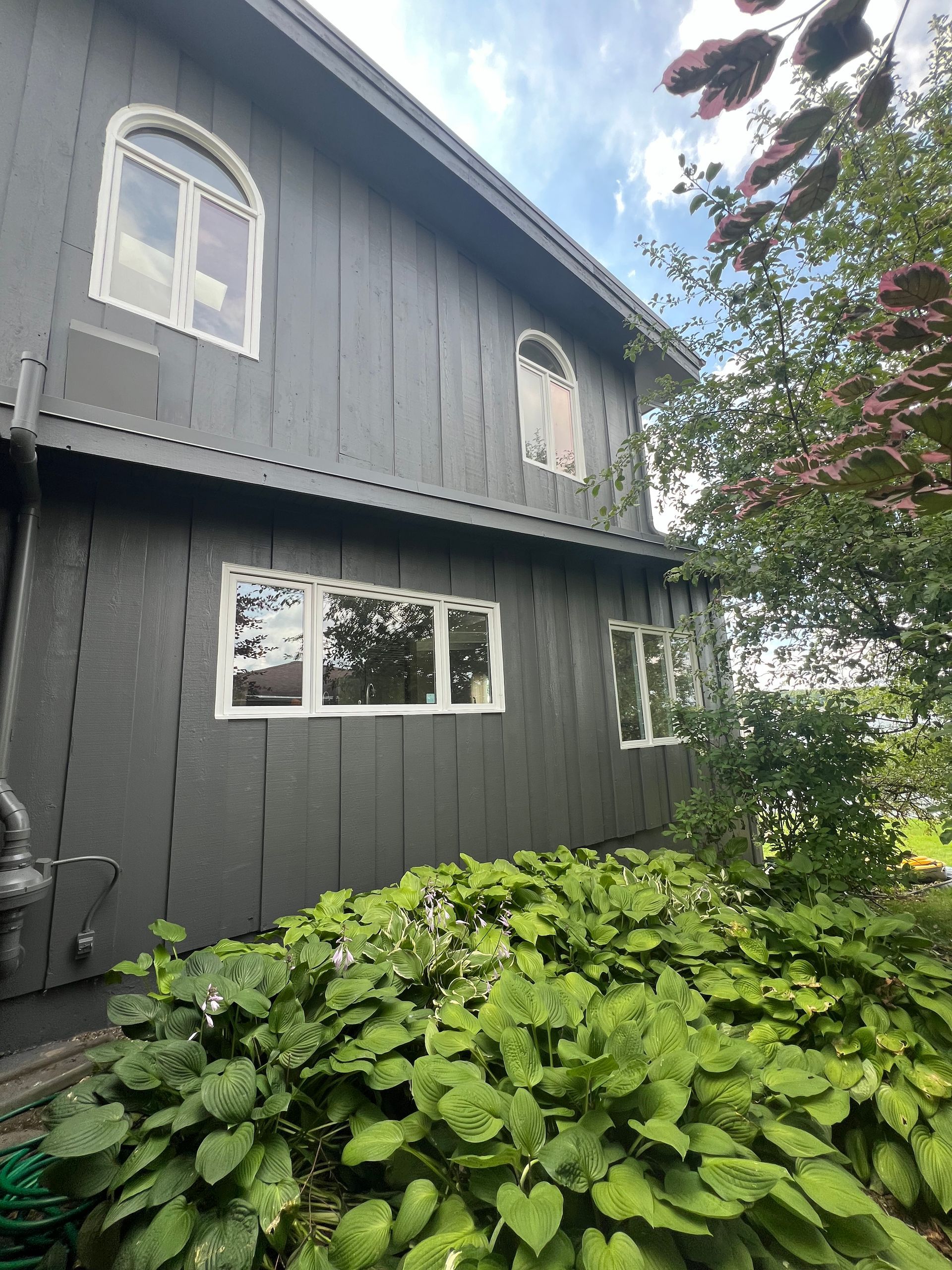 A gray house with a lot of windows and plants in front of it.