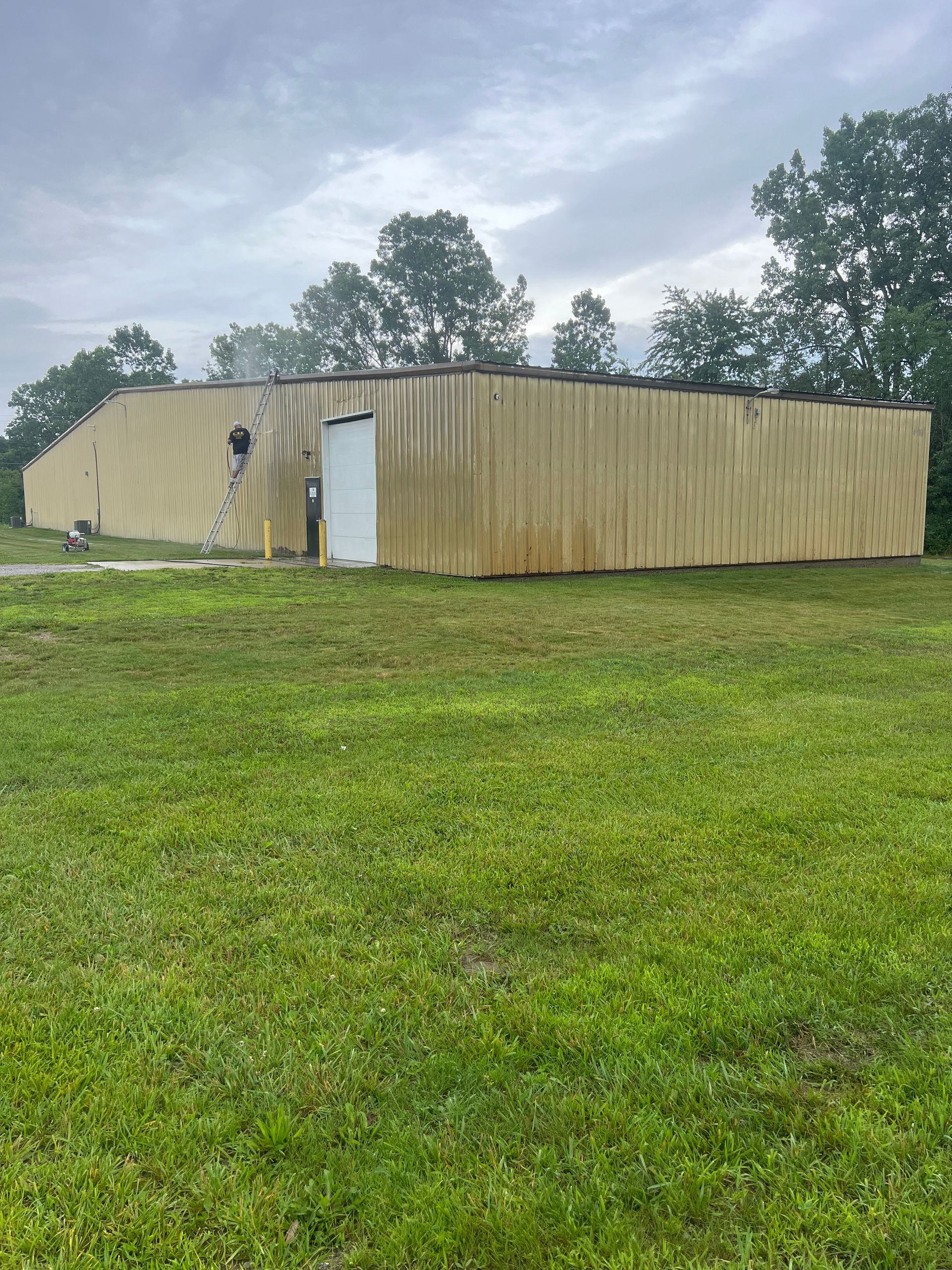 A large wooden building is sitting in the middle of a grassy field.