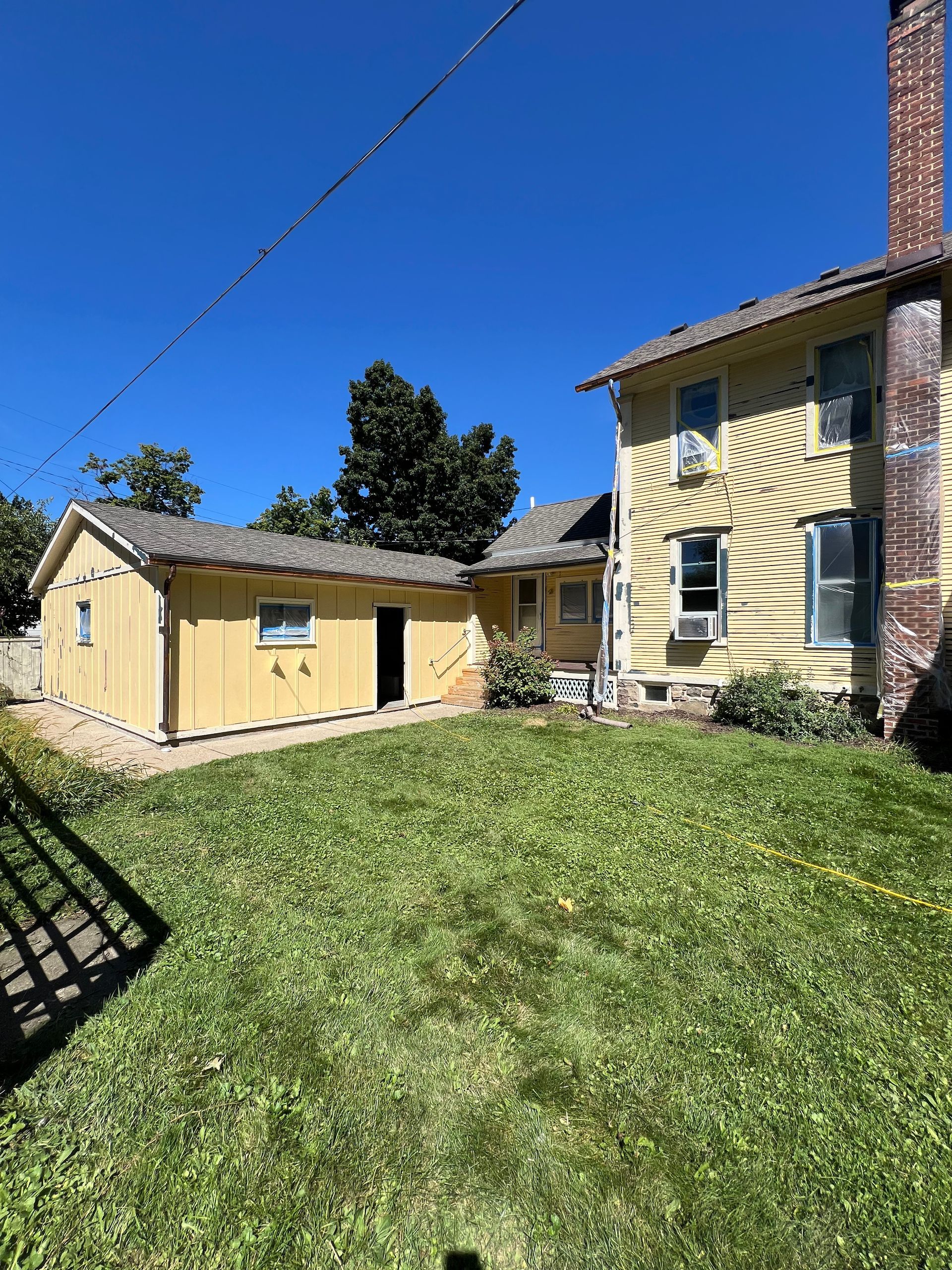 A large yellow house with a shed in the backyard.