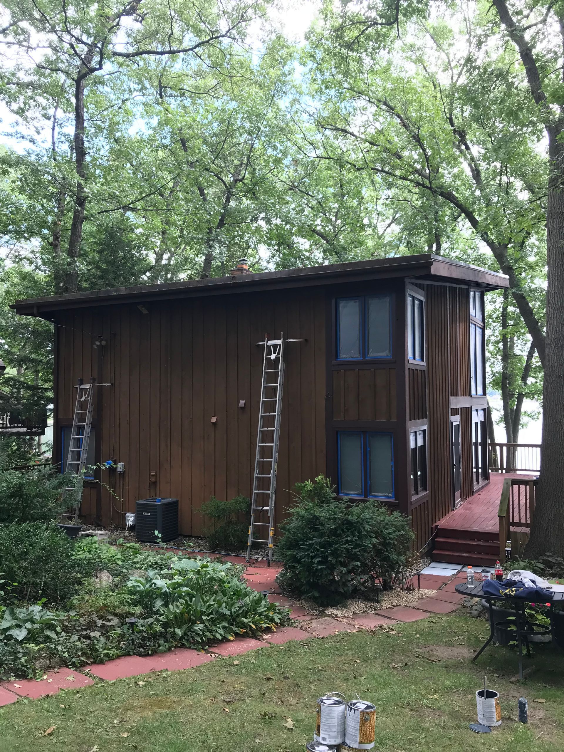 A house is being painted in the woods next to a lake.