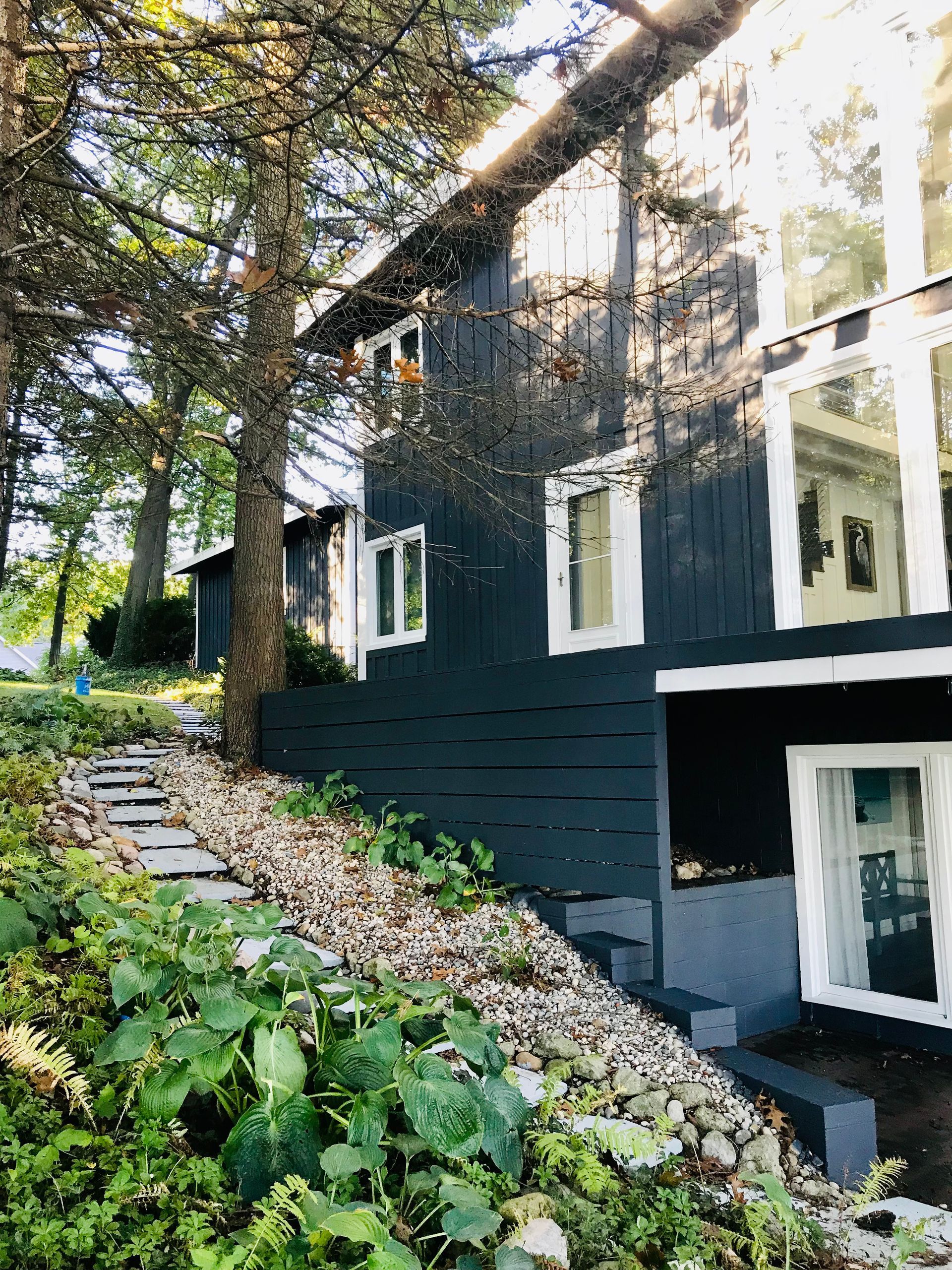 A black house with white windows is surrounded by trees.