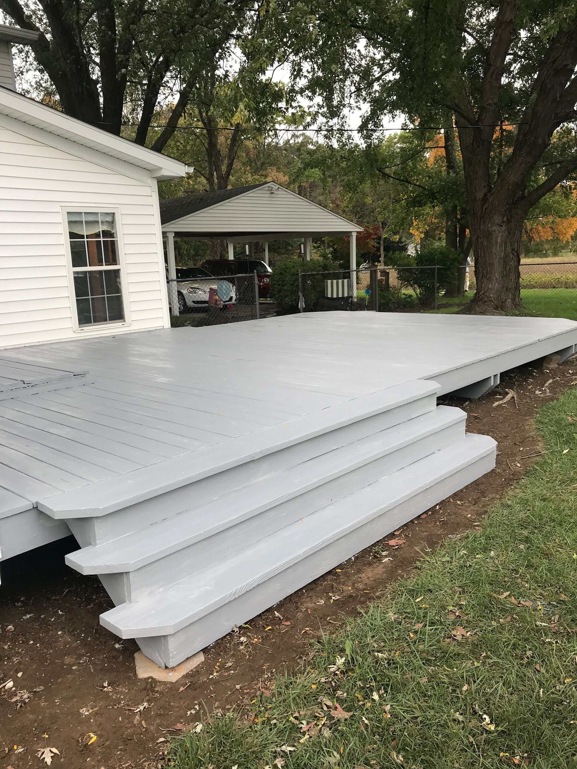 A white house with a white deck and stairs in front of it.