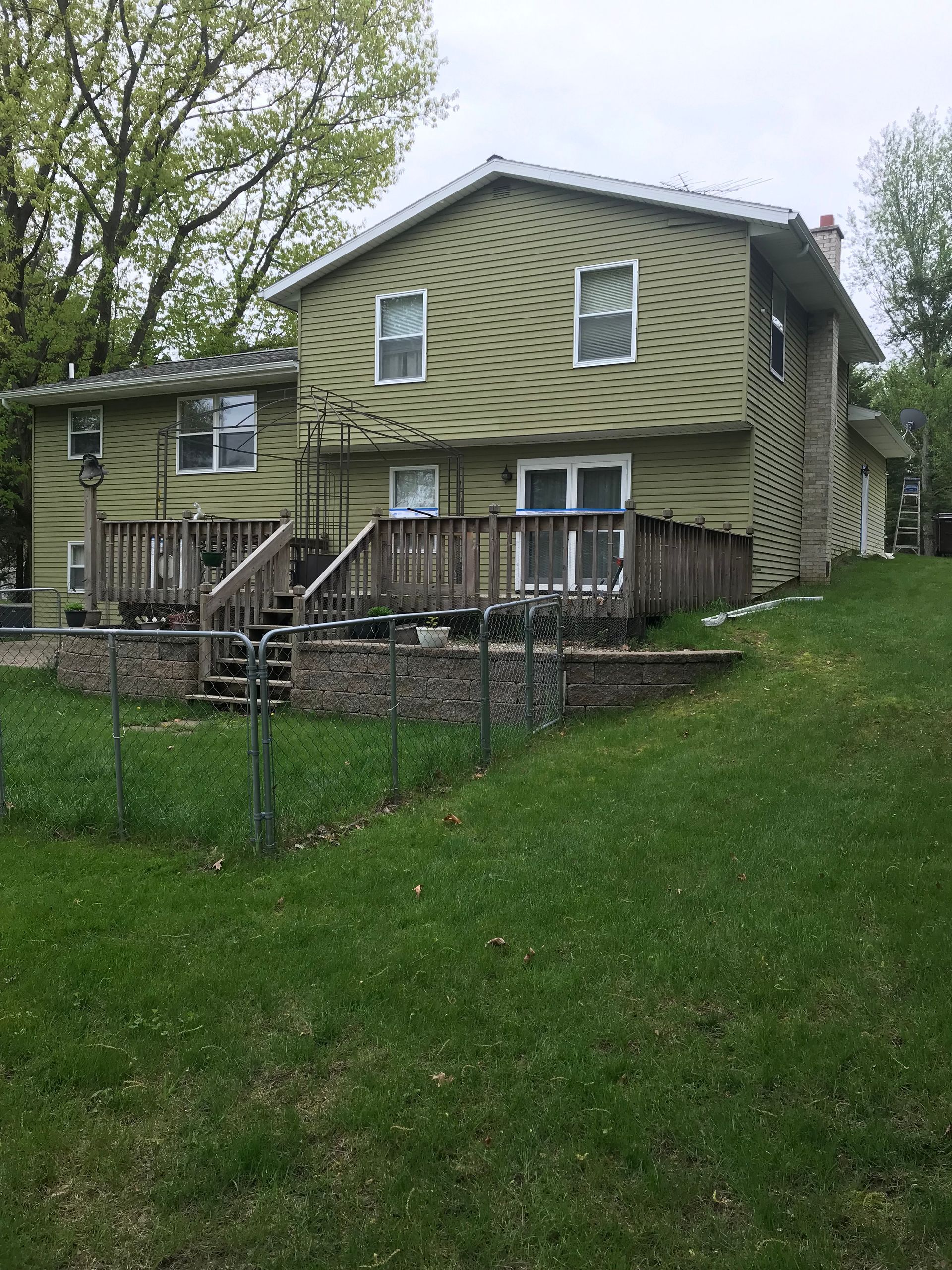 A green house with a deck and stairs in the backyard.