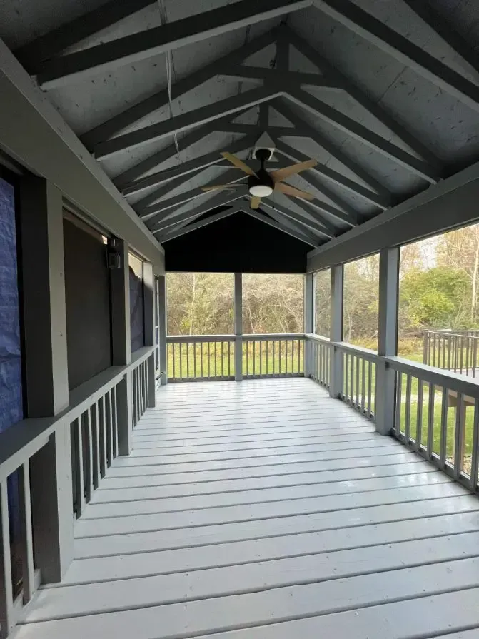 A screened in porch with a ceiling fan.