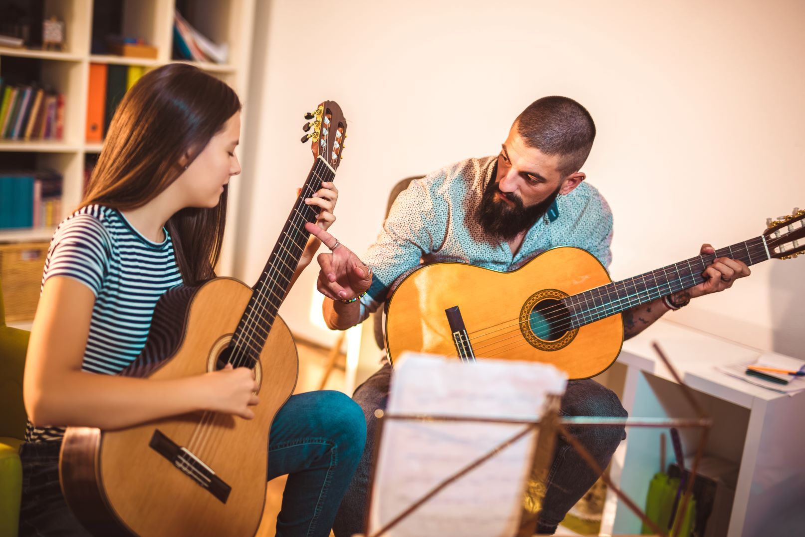 A man and a woman are playing guitars in a living room.
