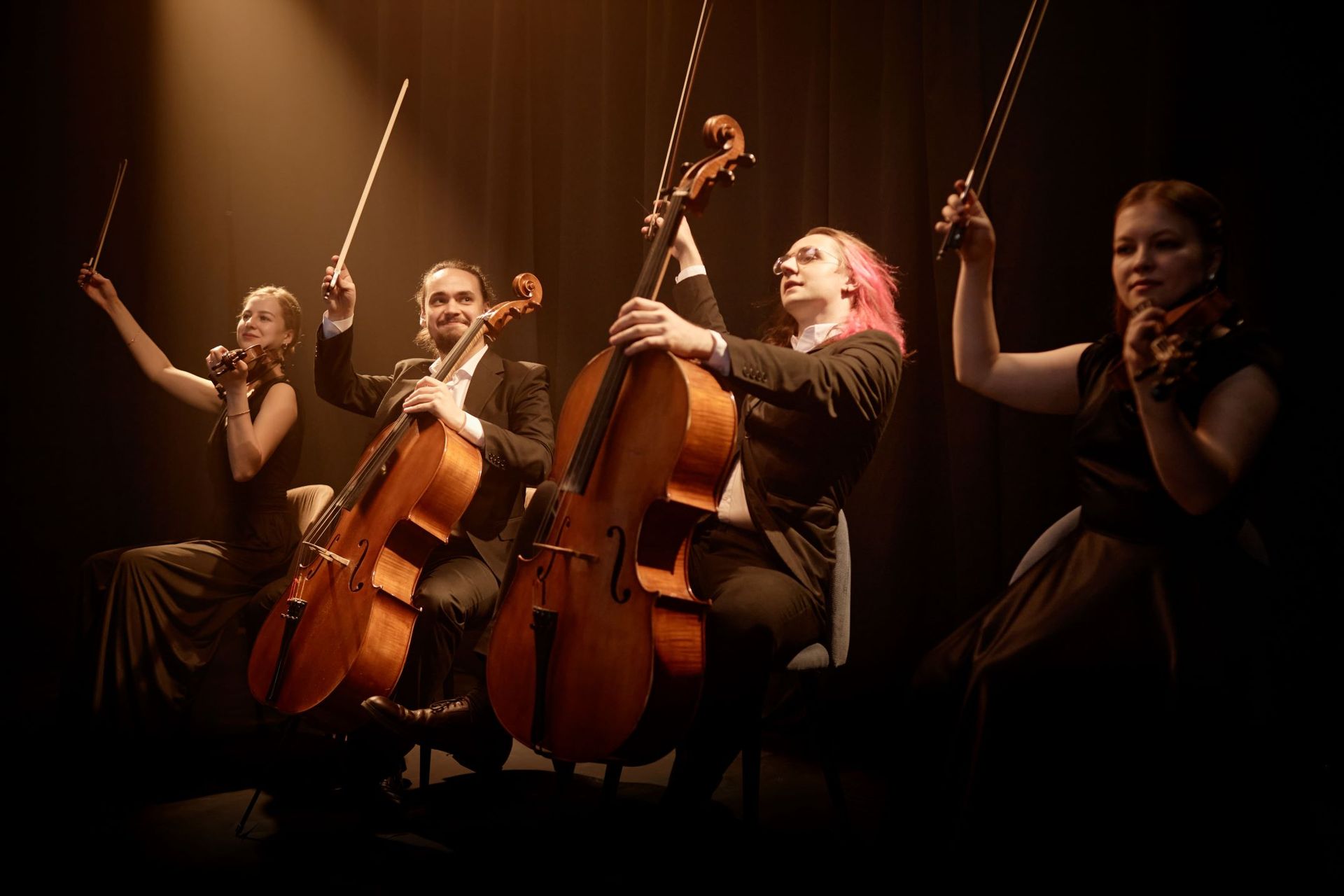 A group of people are playing violins and cello on a stage.