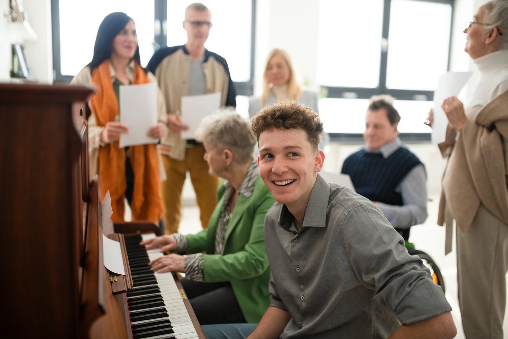 A man in a wheelchair is playing a piano in front of a group of people.