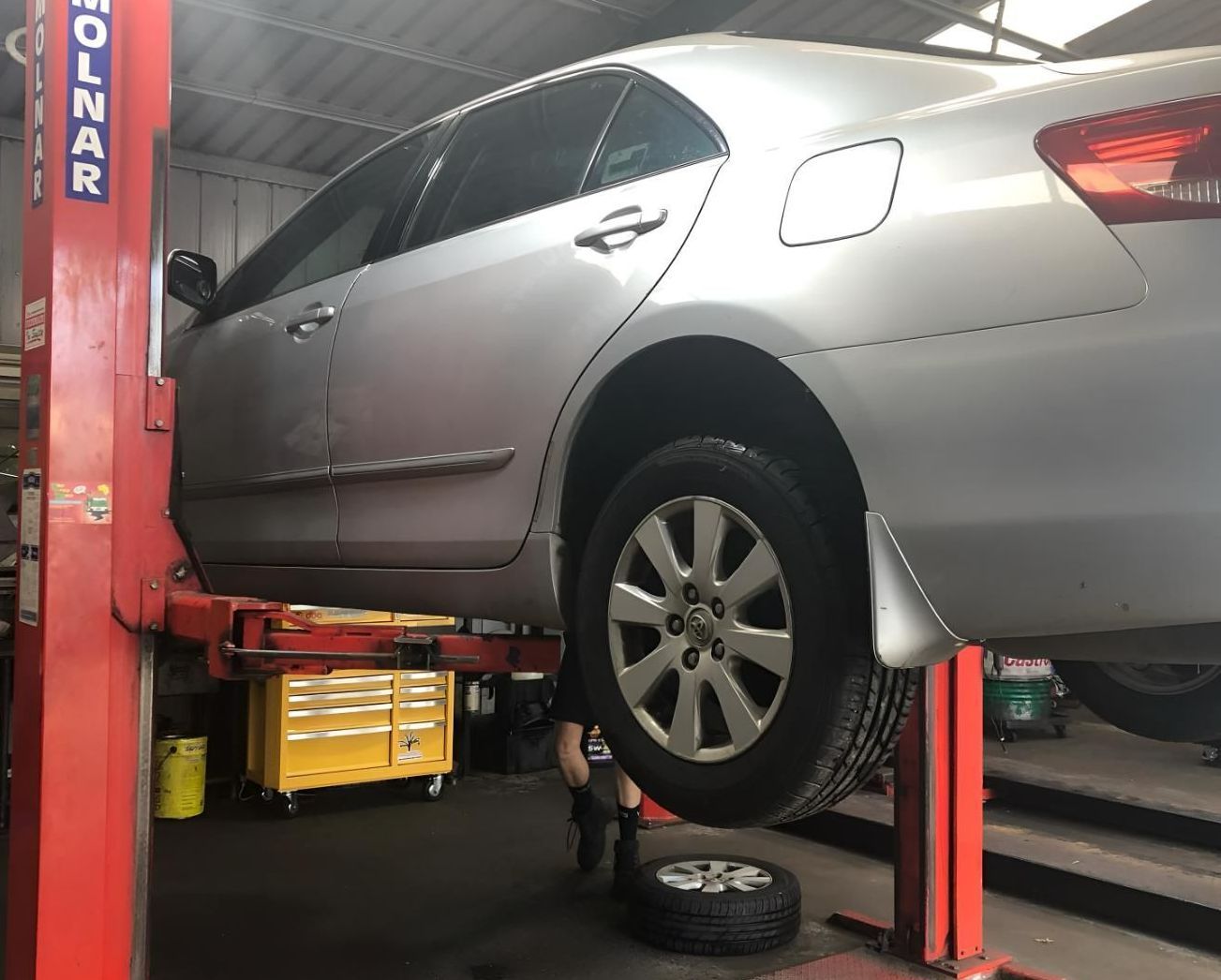 A Silver Car On A Hoist In A Workshop — Coolangatta Automotive in Coolangatta, QLD
