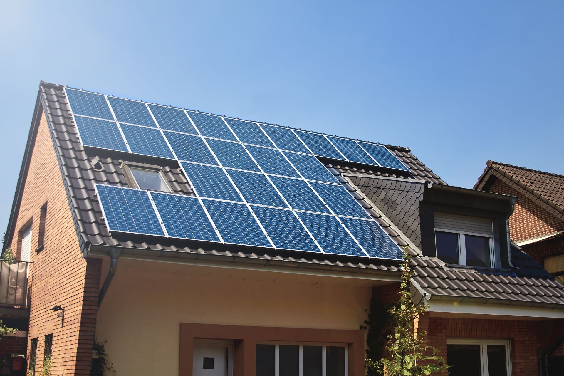 Solar panels installed on a residential home's roof under a clear blue sky.