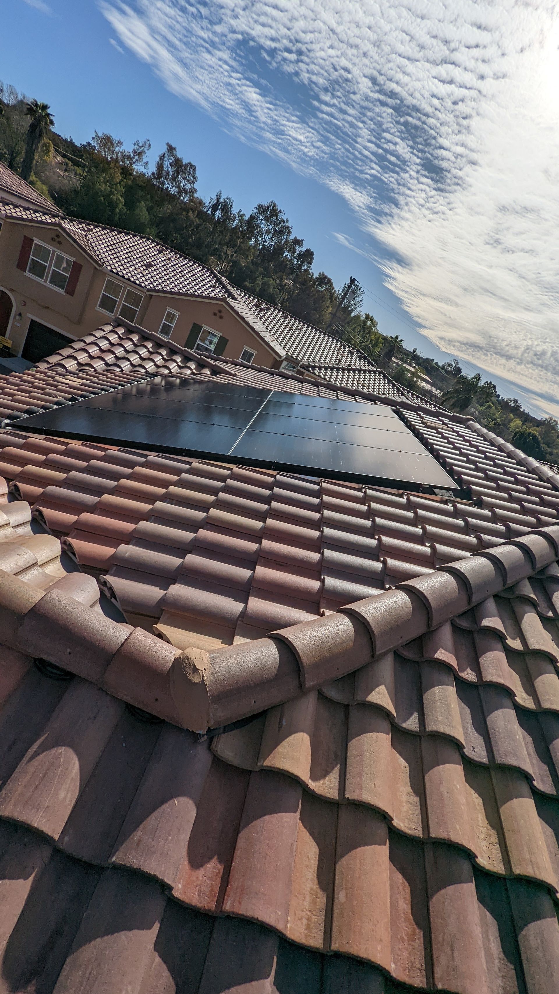 A solar panel is sitting on top of a tiled roof.