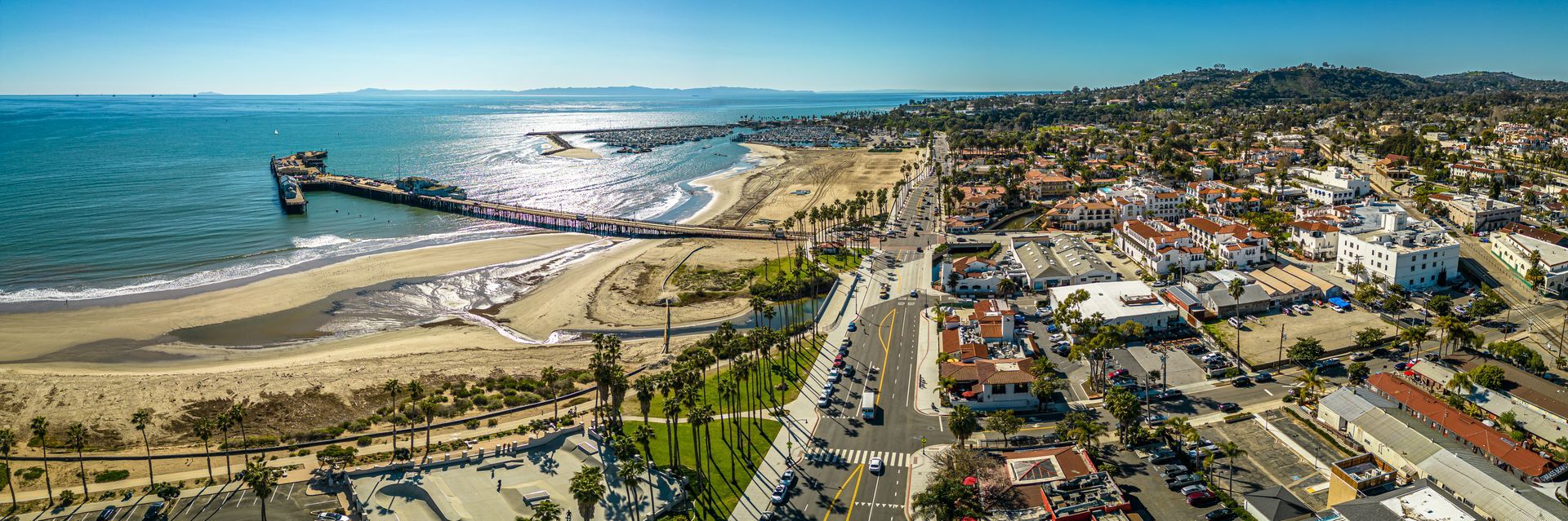 Aerial view of a coastal city with a pier, beach, and buildings.