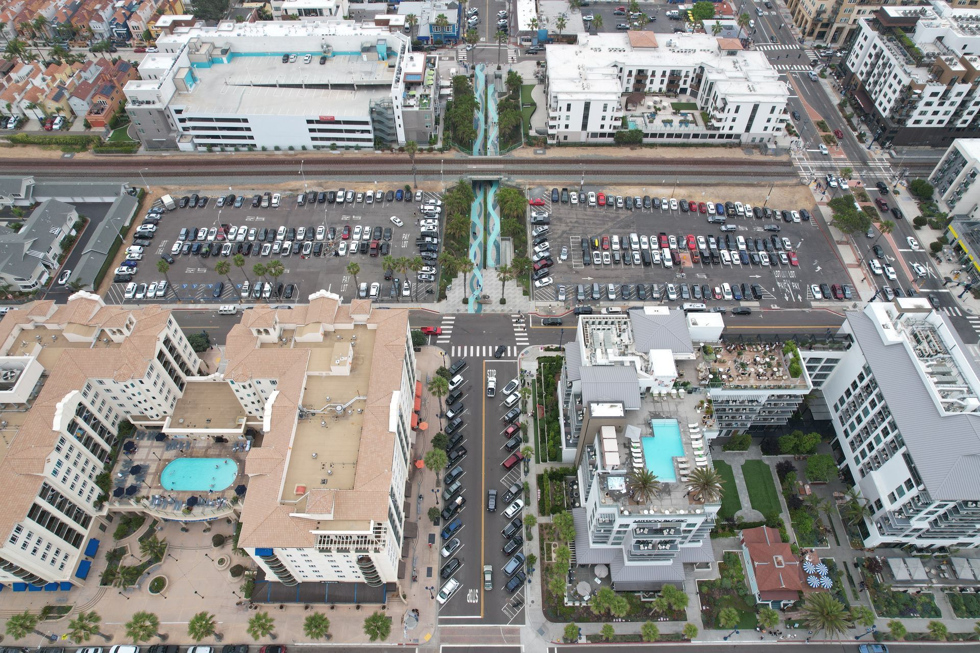 Aerial view of buildings, parking lots, and a pedestrian walkway with water feature.