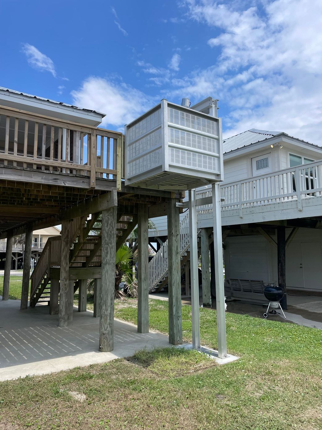 Beach house with a platform lift, under a blue sky.