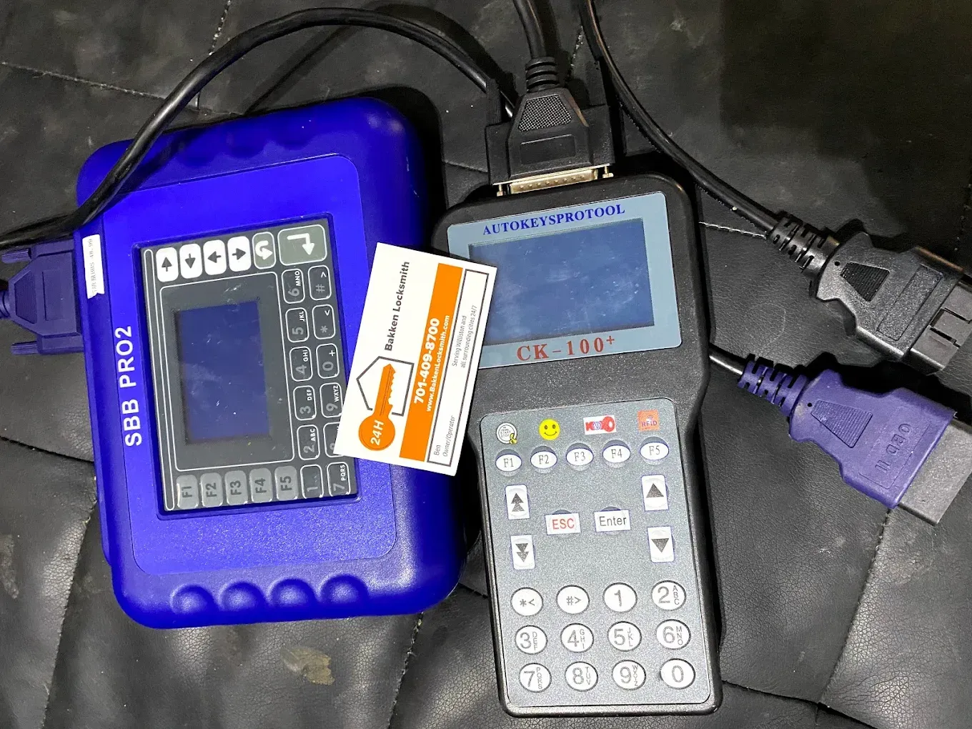 Two car diagnostic tools connected with cables, one blue, one gray, with key card.