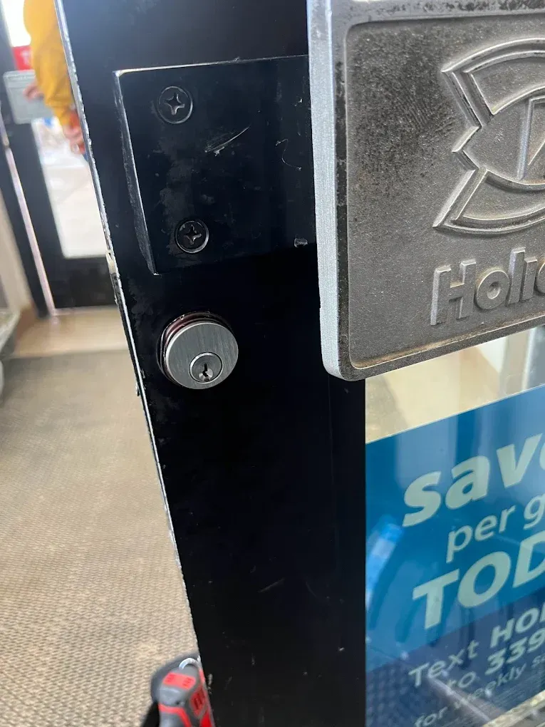 Door lock on a black metal door frame with a sign holder next to it.