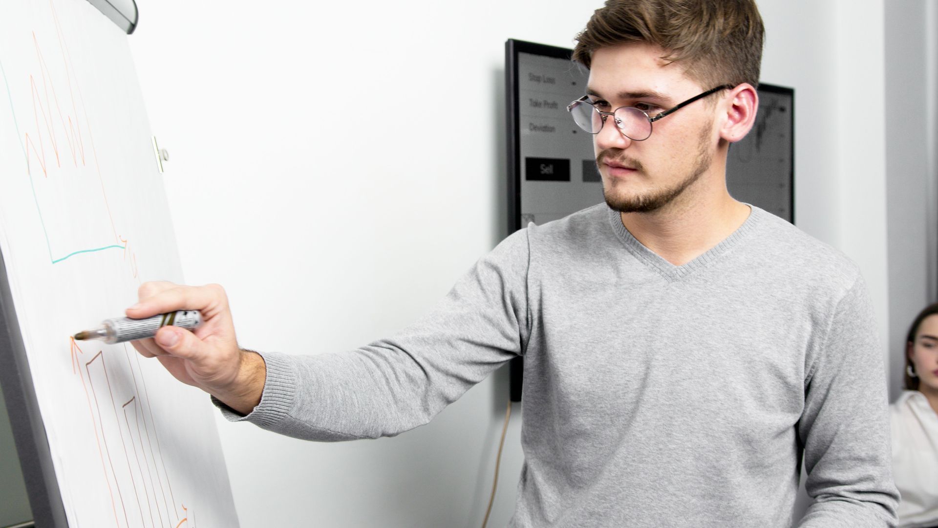 Entrepreneur reviewing operational systems on a whiteboard in a modern office setting