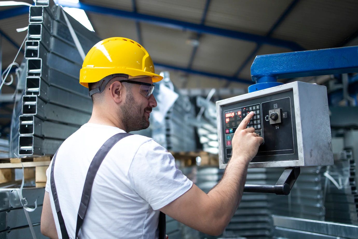 A man wearing a hard hat is working on a machine in a factory.
